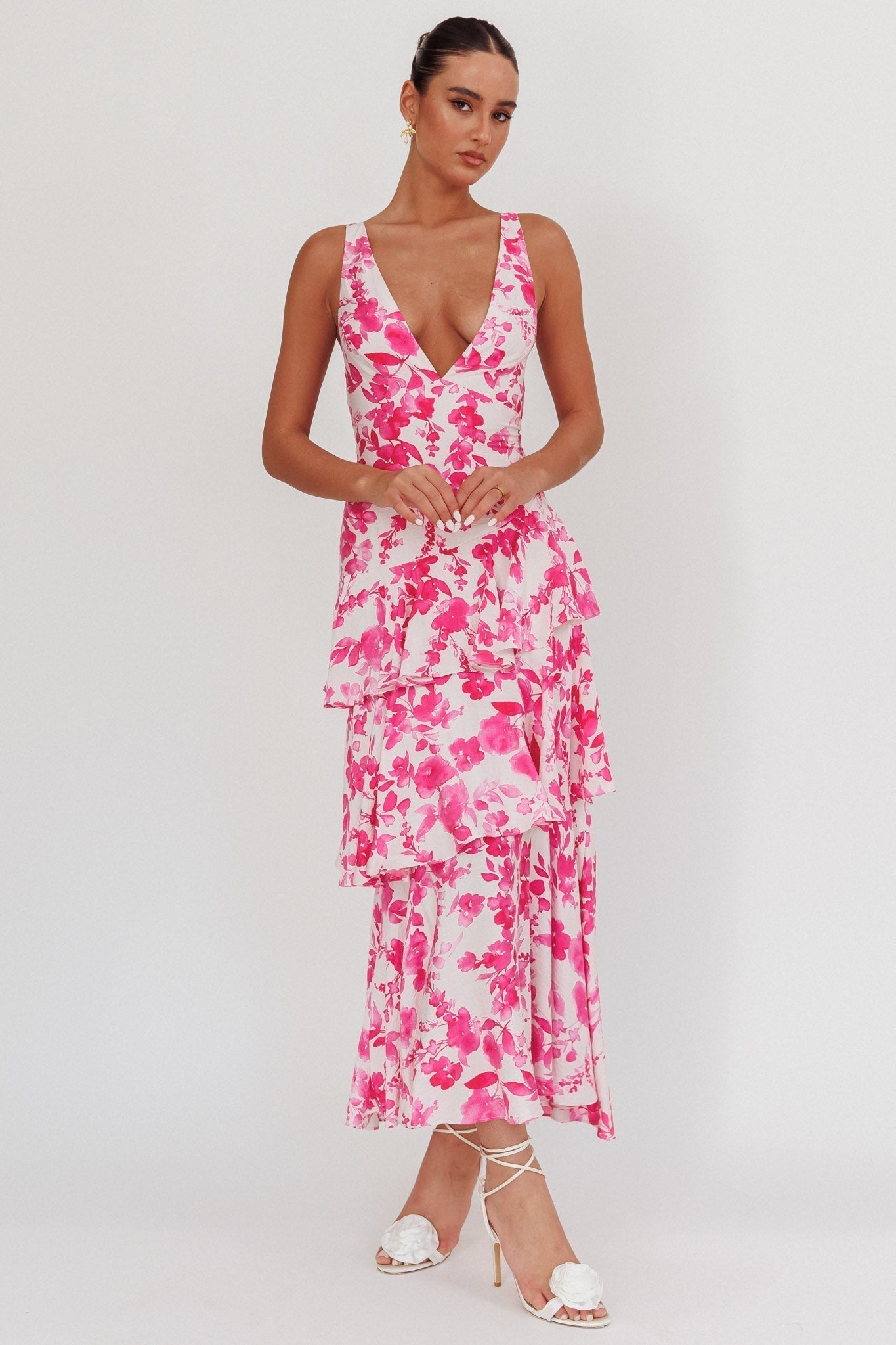 White Harriet Ruffle Maxi Dress with bold fuchsia floral print, deep V-neck, and tiered ruffles for a wedding.