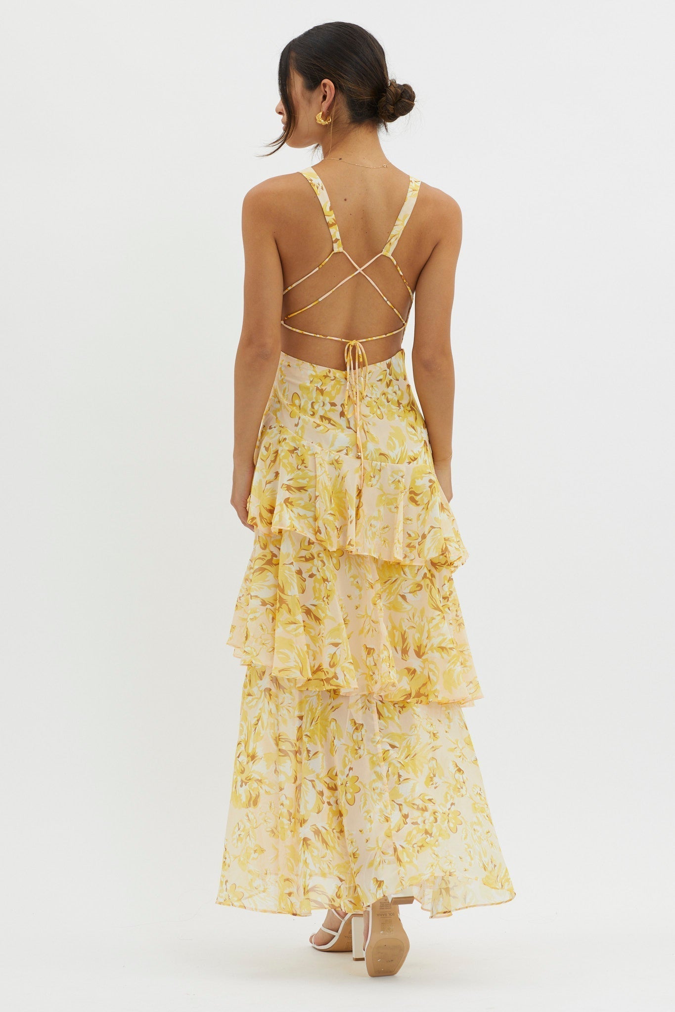 Back view of the yellow floral Harriet Ruffle Maxi Dress, featuring delicate criss-cross straps and tiered ruffles.
