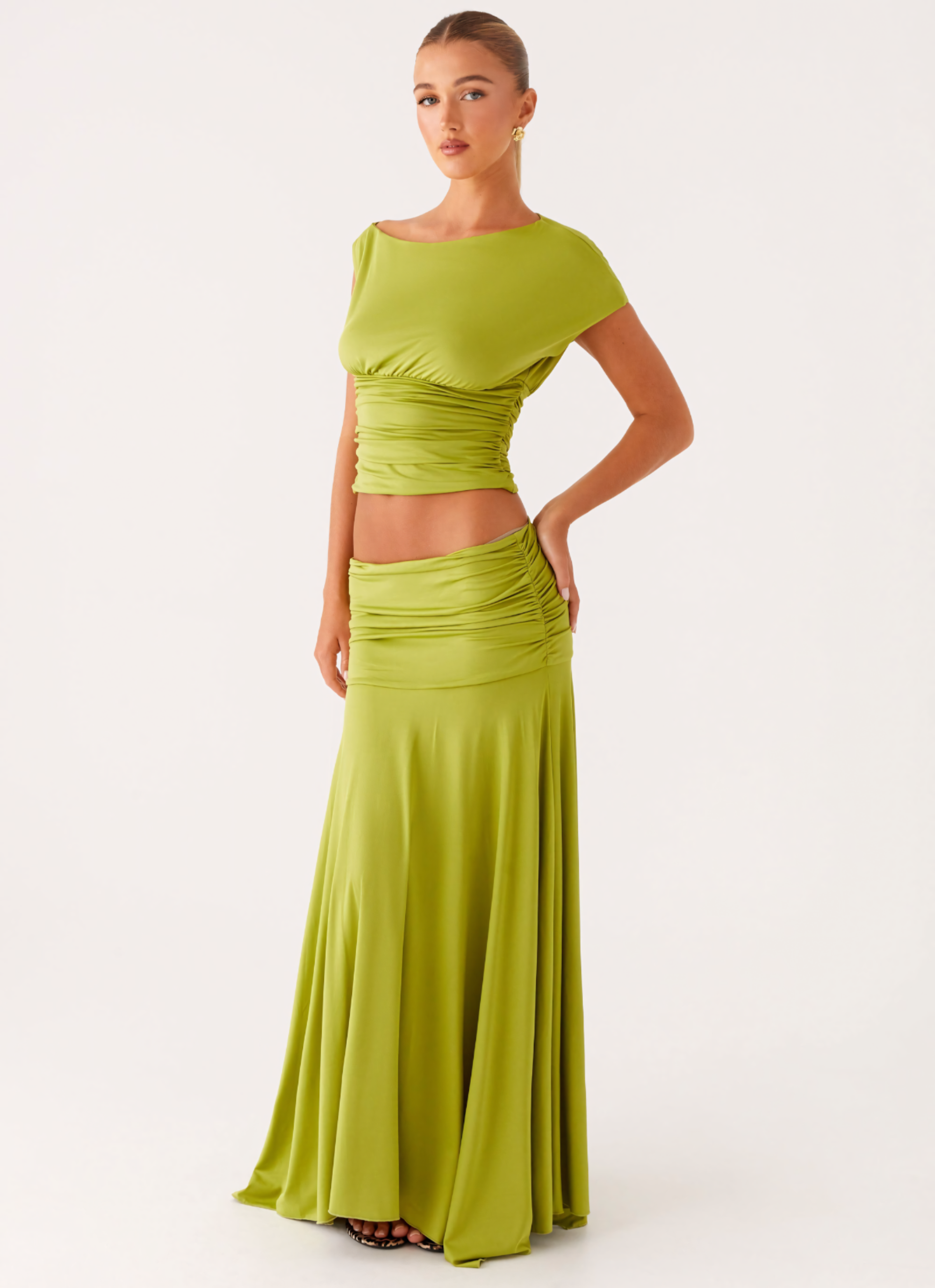 Three-quarter view of a woman in a lime green ruched maxi set, showcasing the fitted crop top and long skirt.