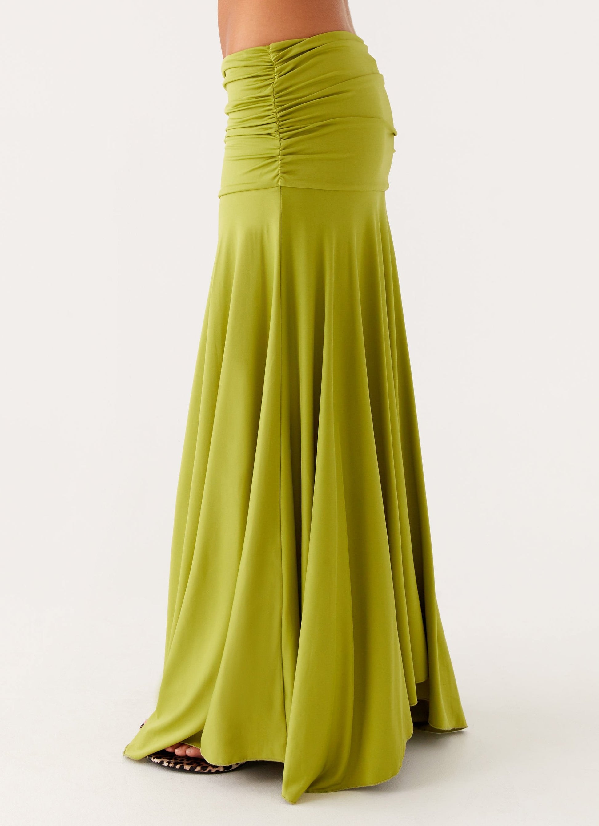 Close-up of the lower half of the lime green ruched maxi skirt, showing the flowing fabric and gathered waistband.