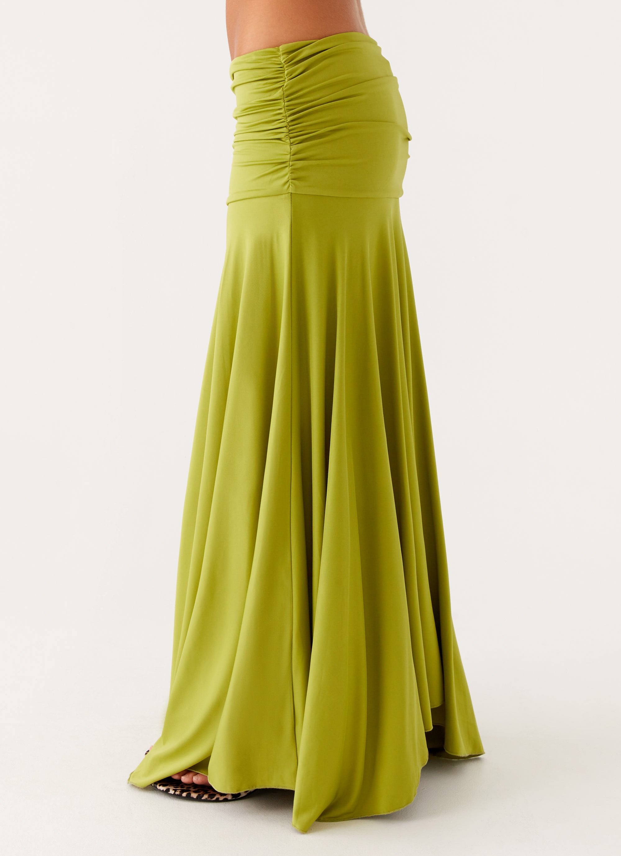 Close-up of the lower half of the lime green ruched maxi skirt, showing the flowing fabric and gathered waistband.