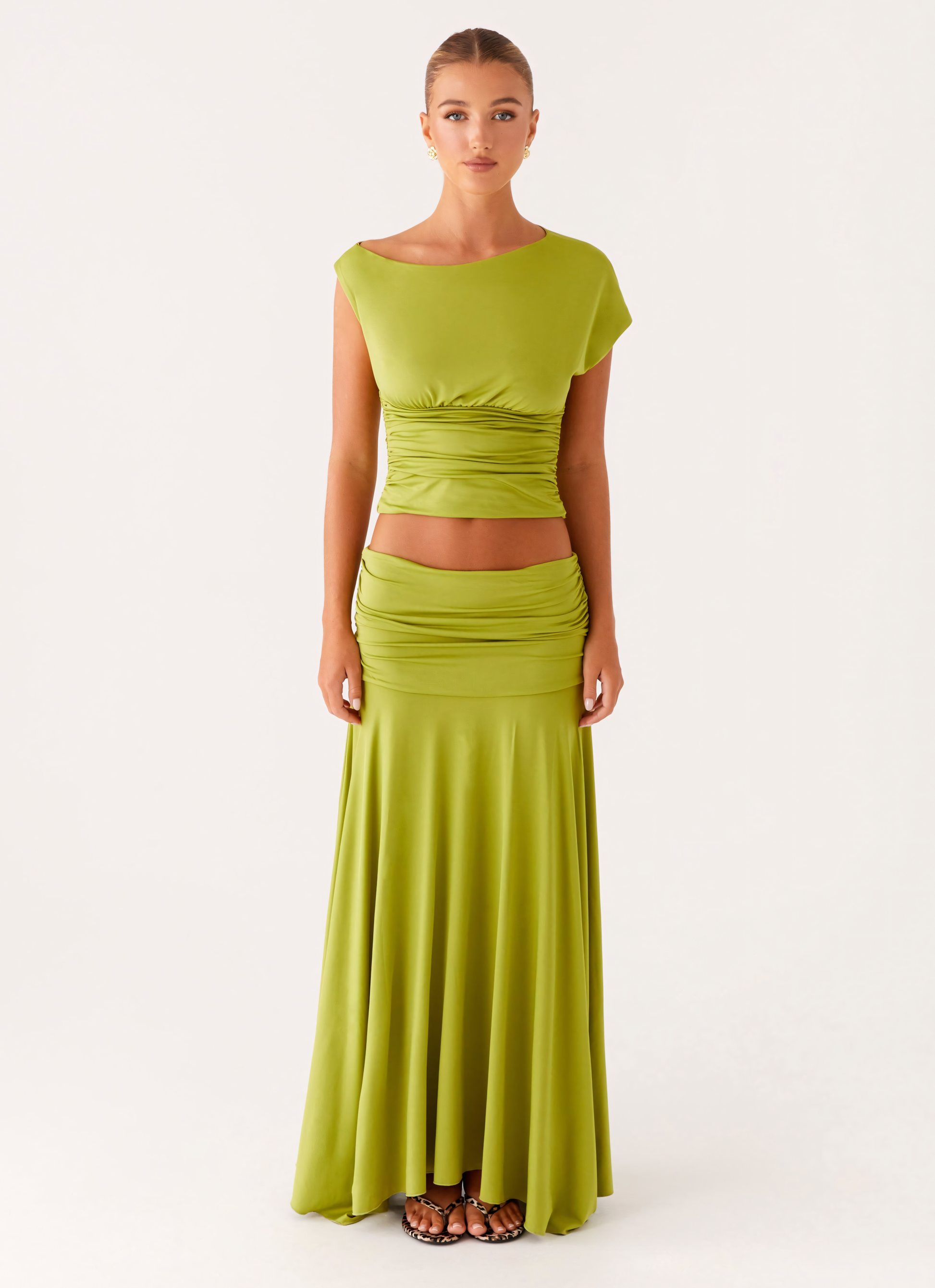 Full-body front view of a woman wearing a lime green ruched maxi set, including a crop top and flowing maxi skirt.