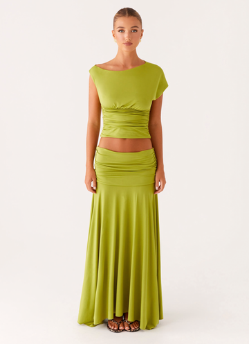 Full-body front view of a woman wearing a lime green ruched maxi set, including a crop top and flowing maxi skirt.