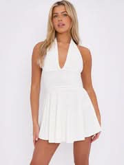Close-up of a white halter neck mini dress featuring a plunging neckline and a textured, pleated skirt.