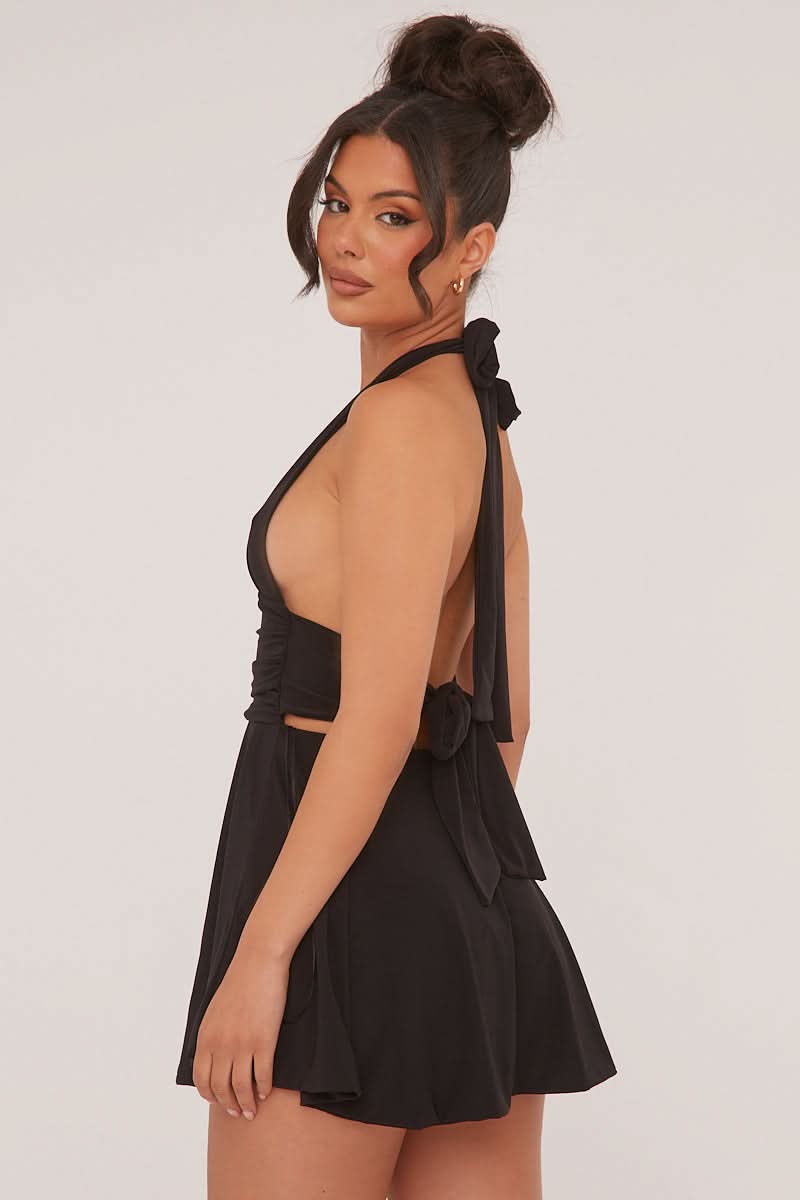 Side profile of the black halter mini dress, highlighting the open back and tie-neck detail.