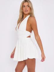 Side profile of a white halter mini dress, showing the cut-out waist and flared mini skirt.