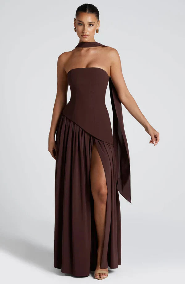 Full-length dark brown asymmetrical maxi dress with a strapless design, high leg slit, and matching neck scarf.