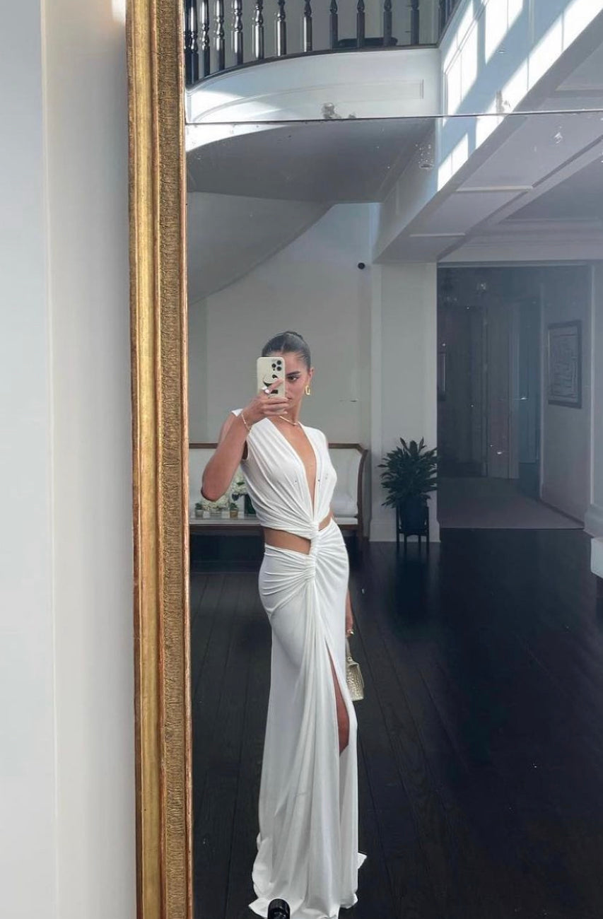White Robyn cutout maxi dress with plunging V-neck and high slit, reflecting in a large gold-framed mirror.