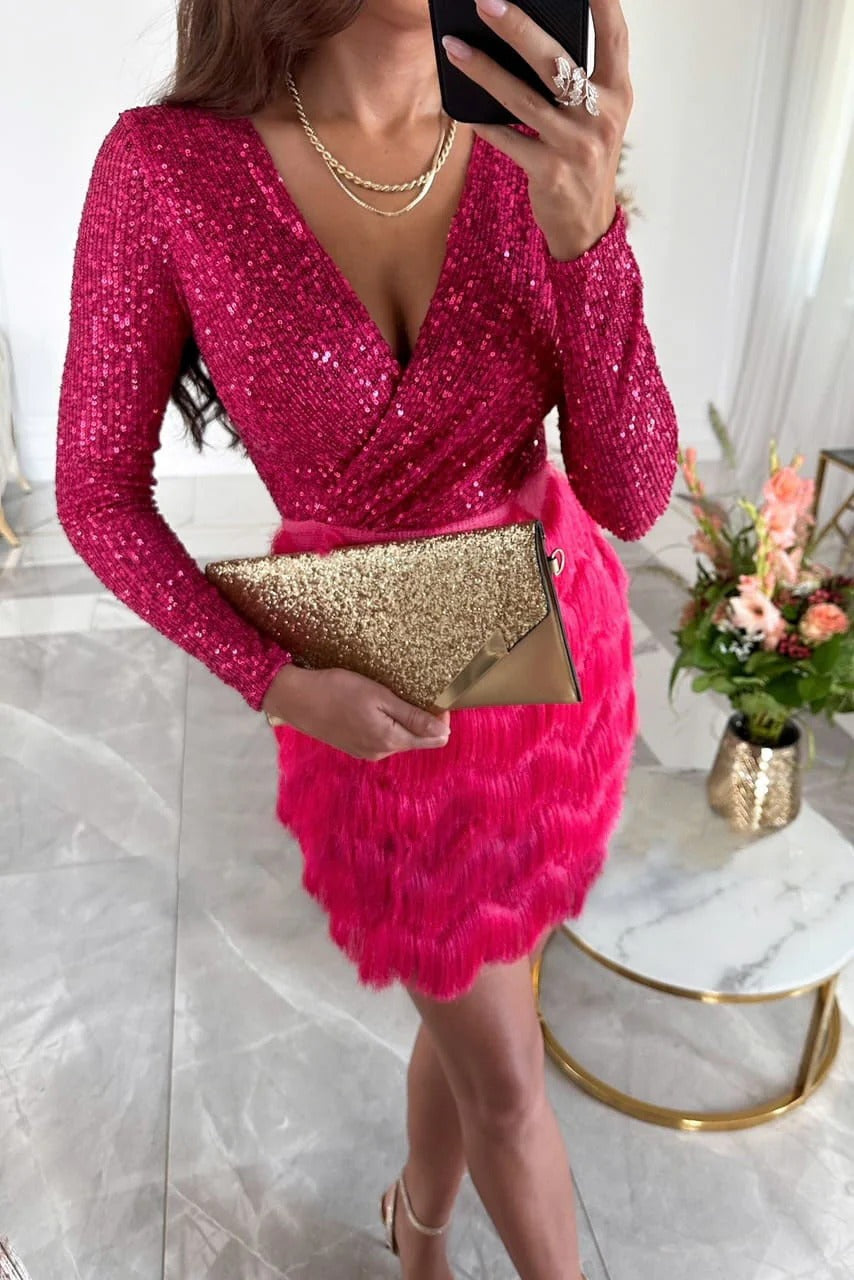 Close-up of a hot pink sequin long-sleeve mini dress with a vibrant pink fringe skirt, paired with a gold glitter clutch.