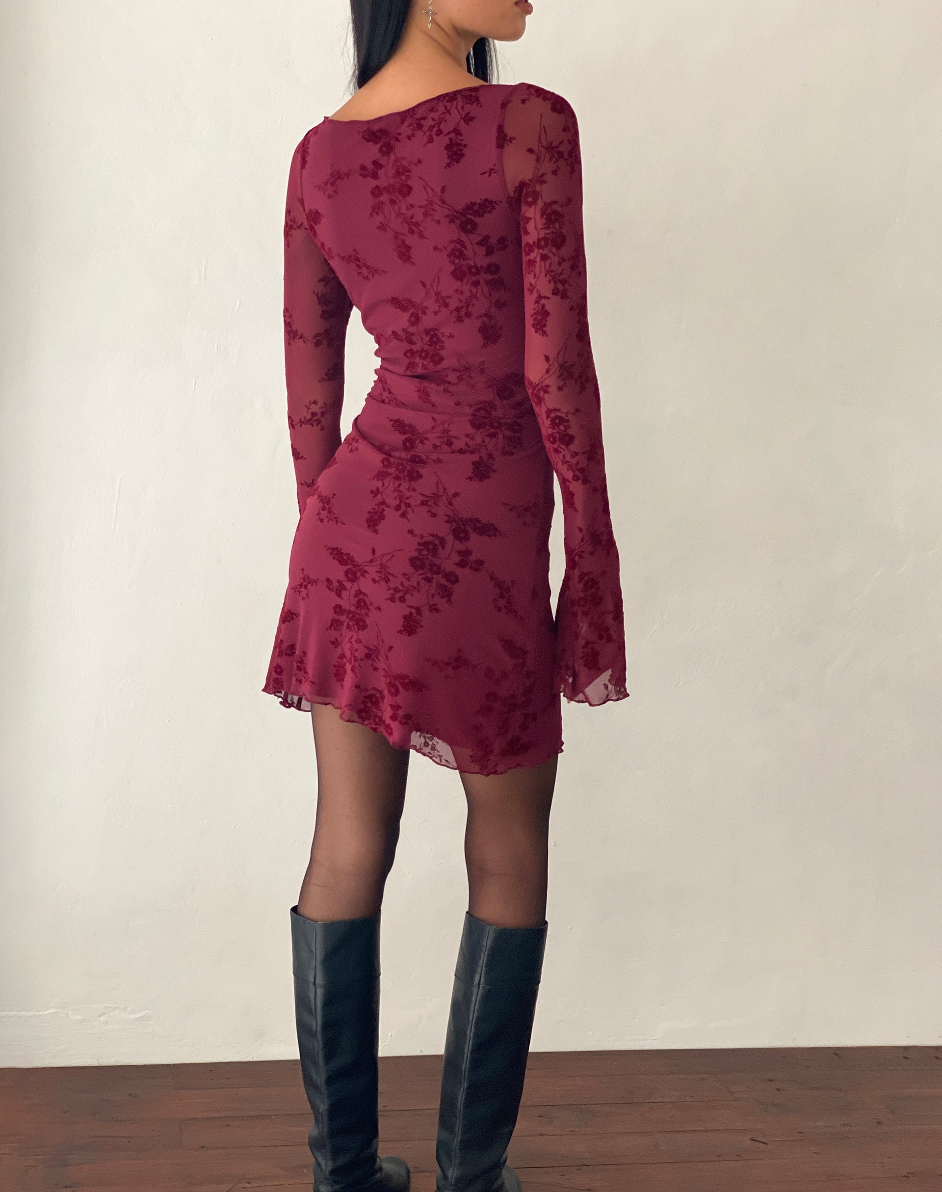 Back view of a model in the dark red Rosalie Scalloped Mini Dress, highlighting the boat neckline and long sleeves.