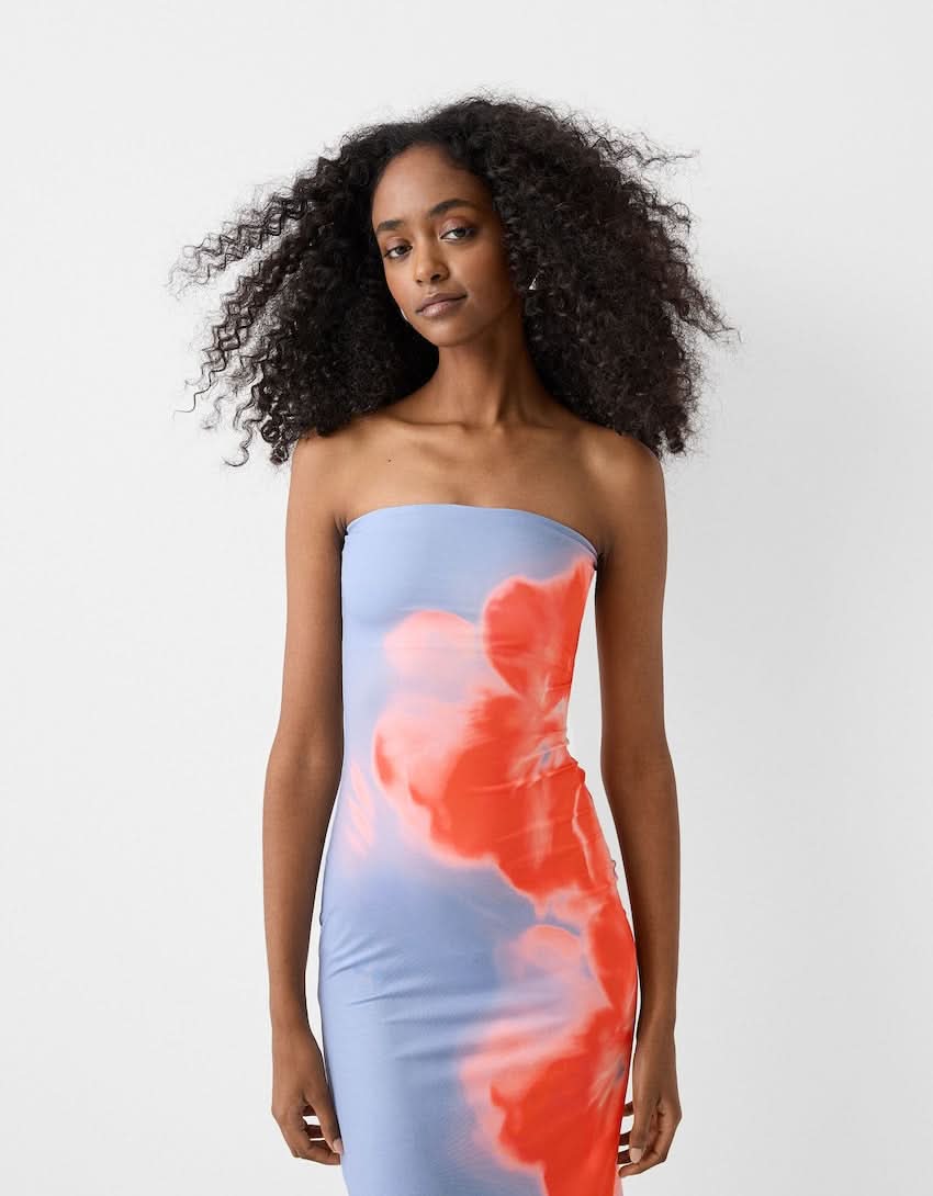 Close-up front view of a woman wearing the blue strapless maxi dress with blurred floral print.