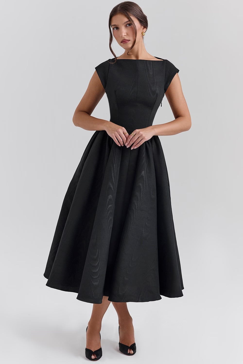 Front quarter view of the black Sara open-back midi dress, showcasing the textured fabric and fitted waist.