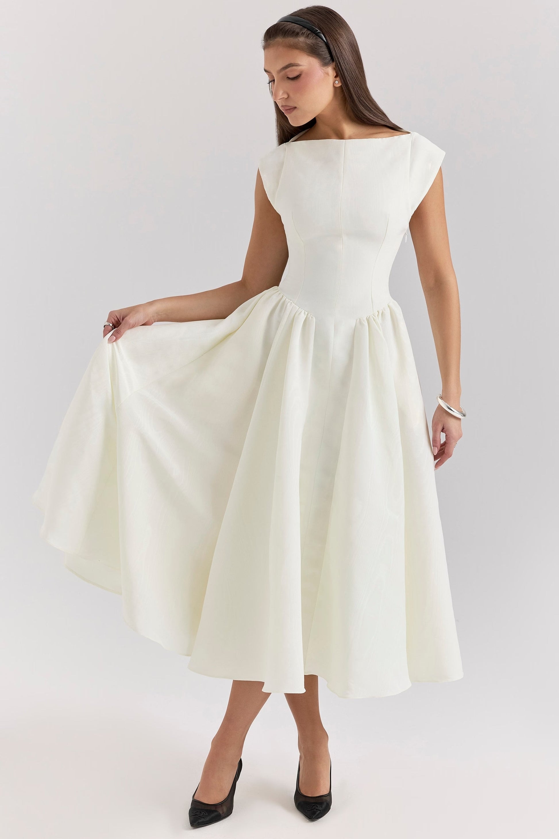 Front view of the white Sara open-back midi dress, with the model holding out the skirt to show its fullness.