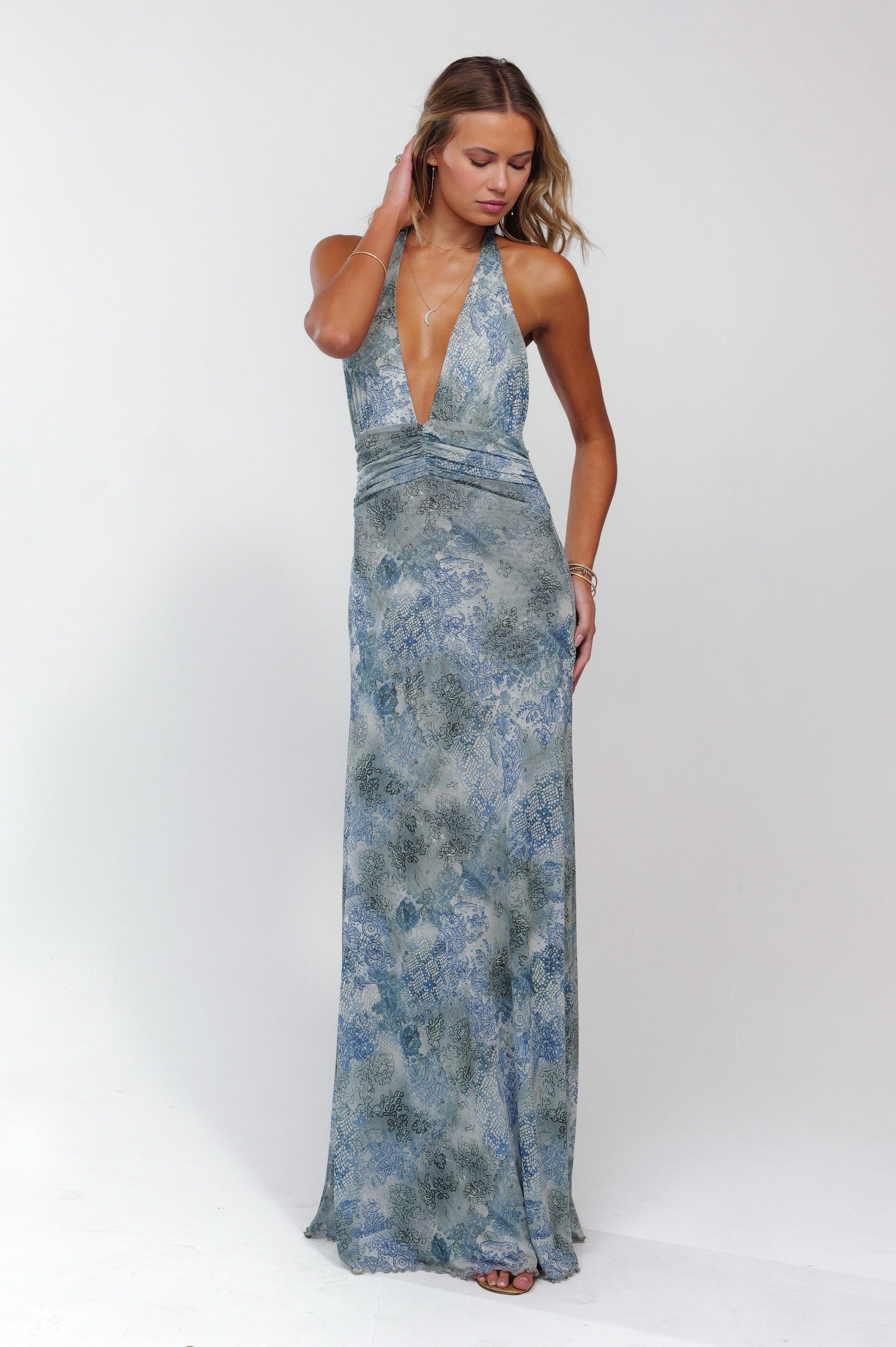 Full length view of a light blue and grey patterned maxi dress with a deep plunge neckline and ruched waist detail.