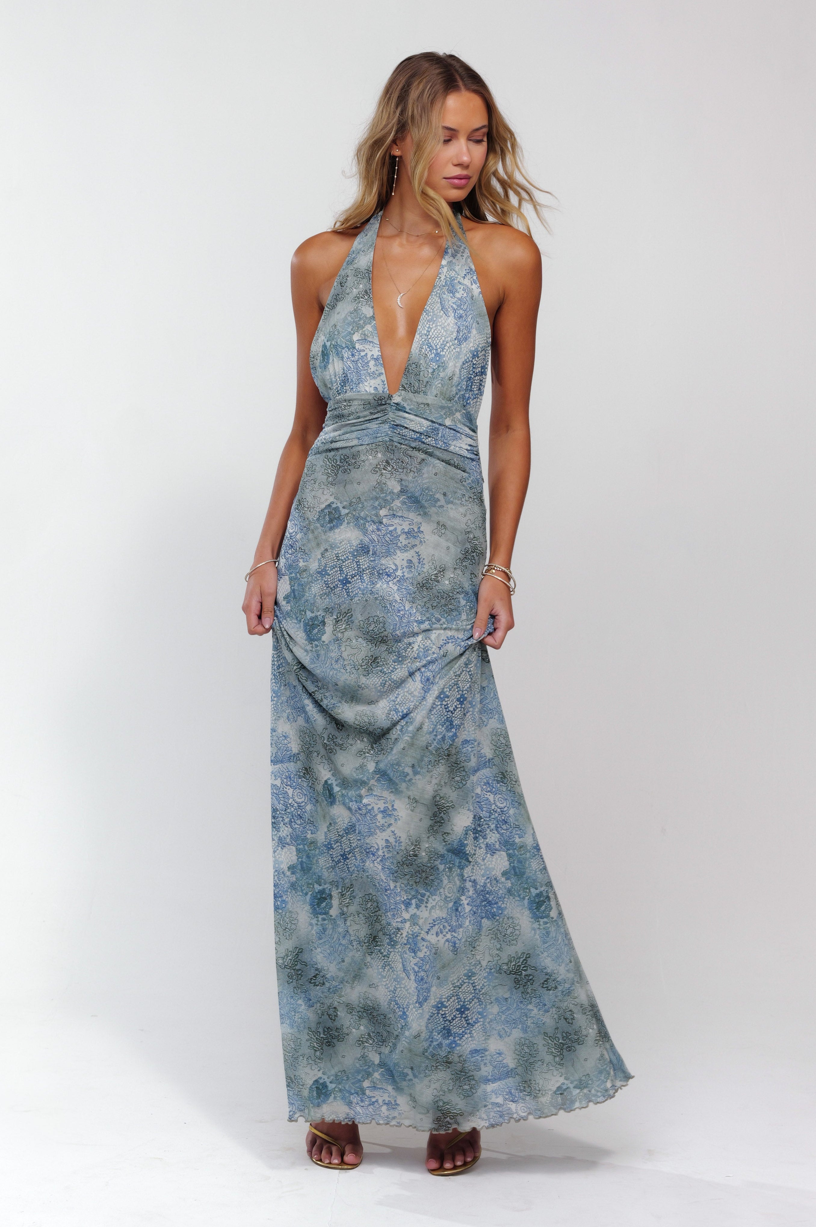 Front view of blue patterned plunge maxi dress with deep V-neck, ruched bodice, and long skirt.