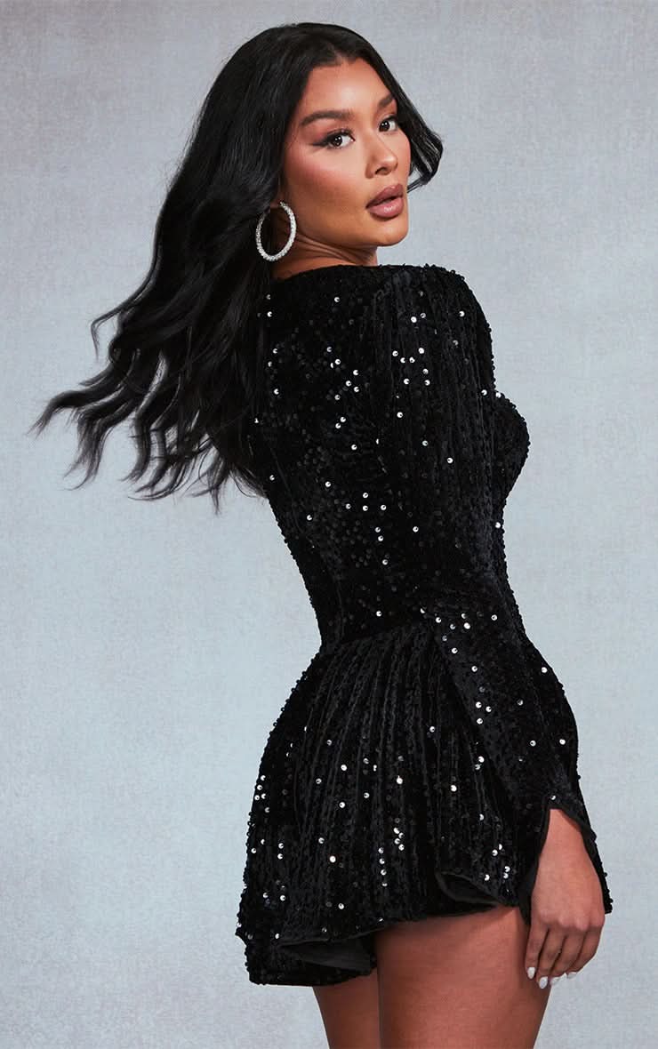 Side view of the black sequin mini dress, highlighting the long sleeves and flowy pleated skirt design.