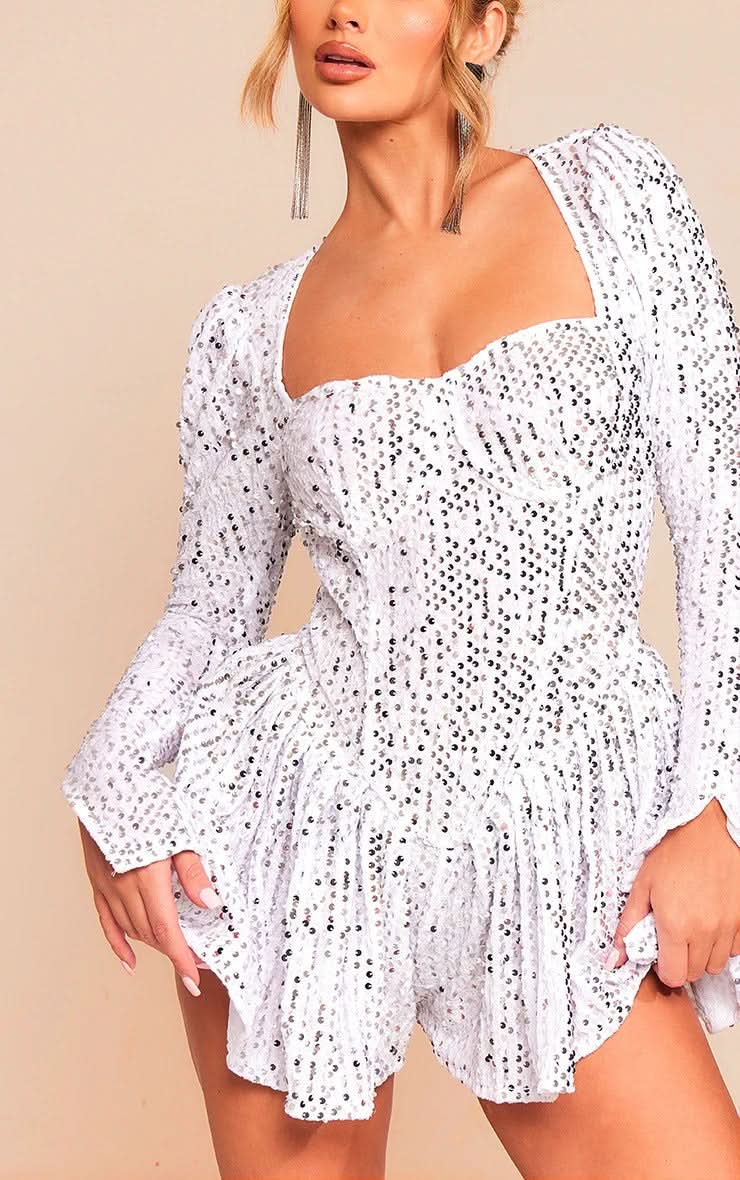 Close-up of the white sequin mini dress, showing the square neckline and textured sequin fabric.