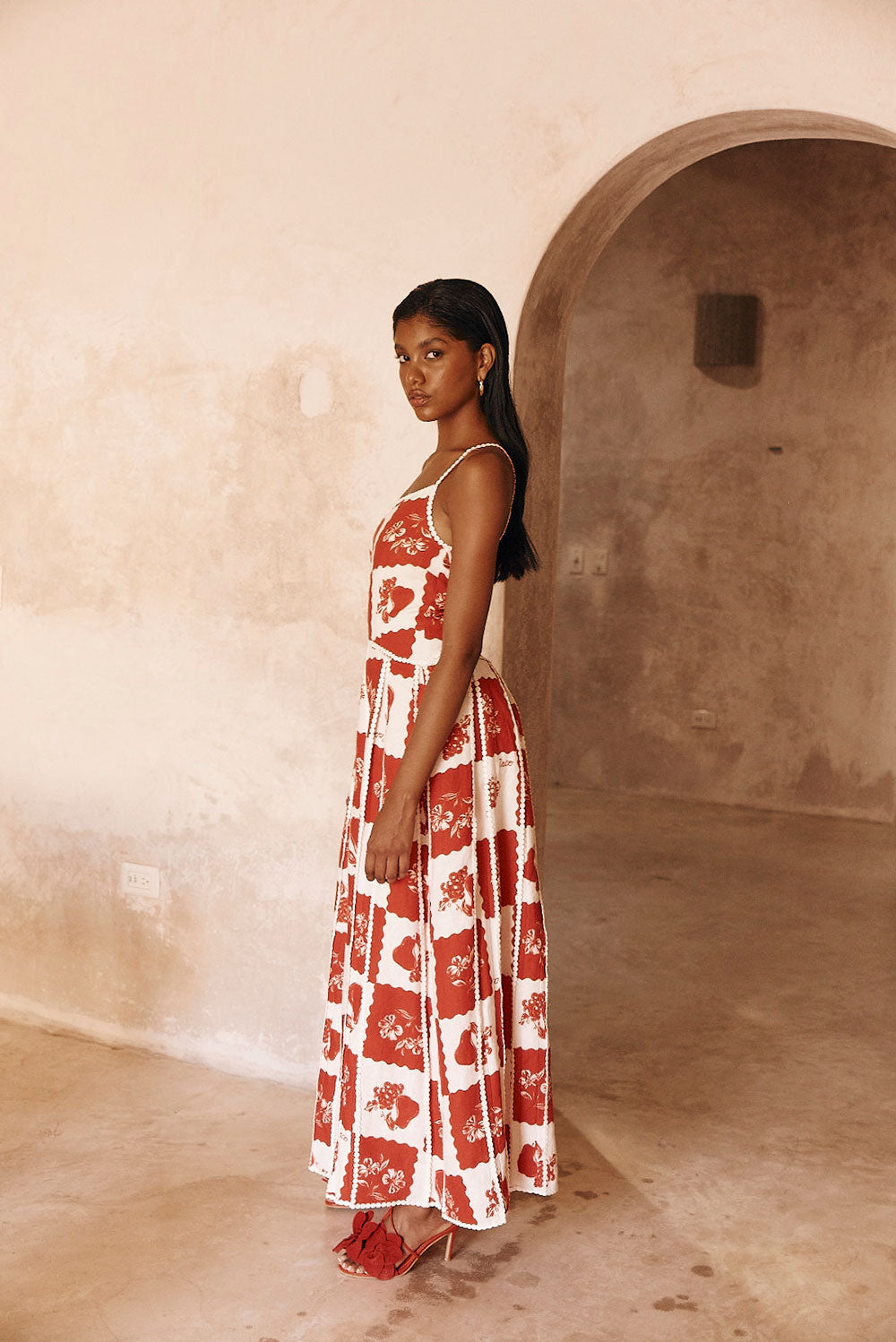 Side profile of Savannah one-shoulder maxi dress, red and white checkered print, with scalloped edges.
