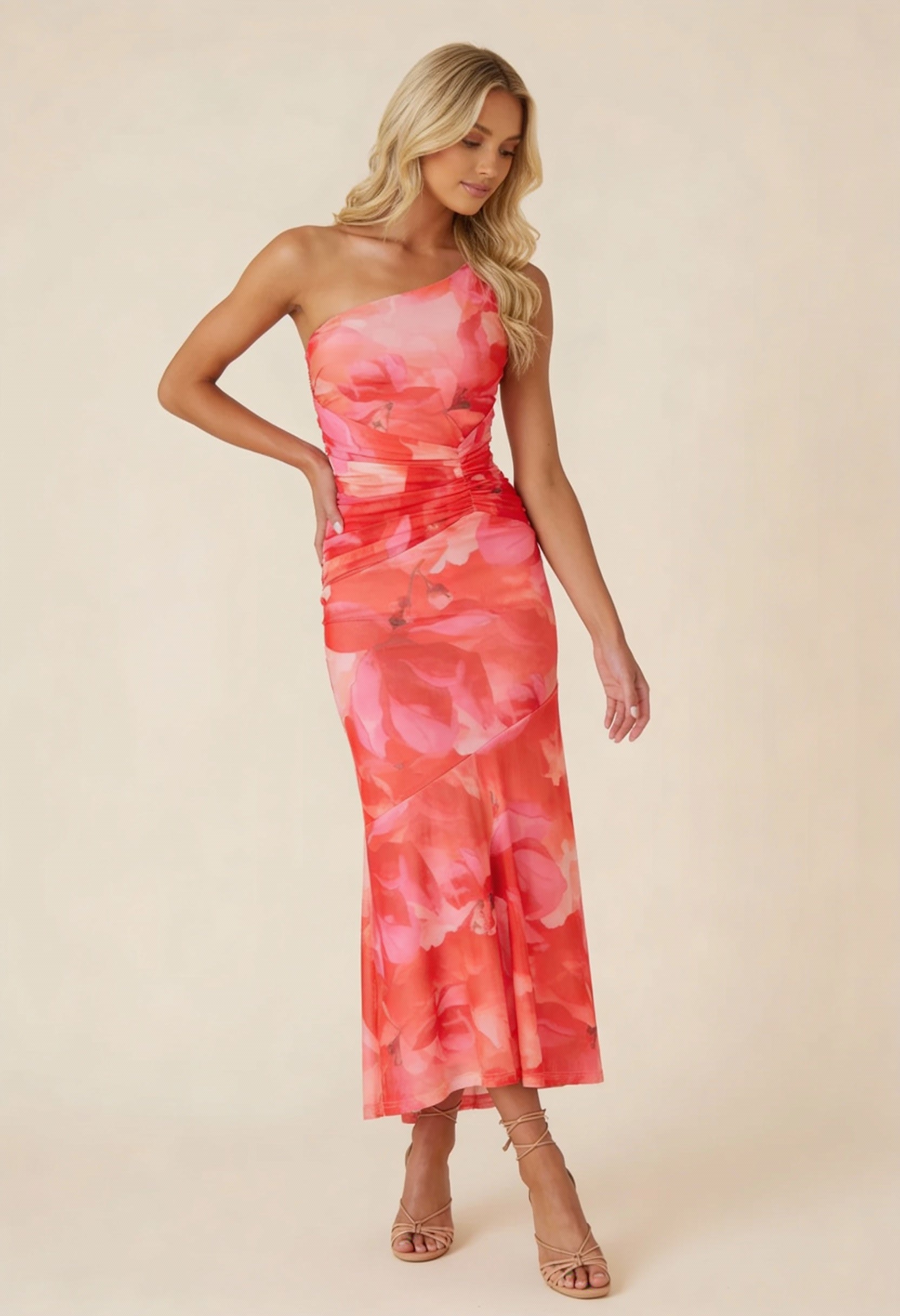Red and pink floral one-shoulder ruched maxi dress with a high-low hem, side pose with hand on hip.