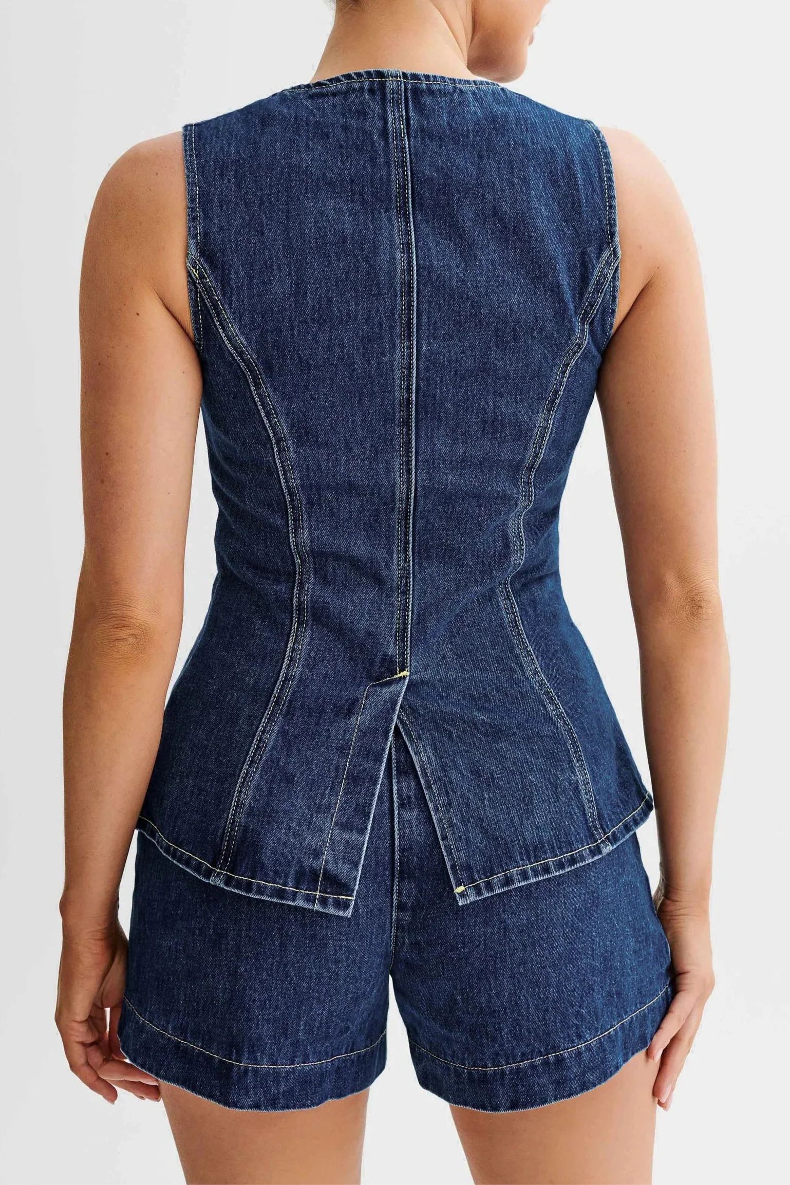 Back view of the dark blue denim Sienna button top and shorts set, highlighting the tailored fit and back slit detail.