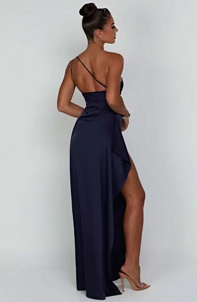 Rear view of a navy blue Sienna Draped Maxi Dress with a single spaghetti strap and high slit, showcasing the flowing fabric.