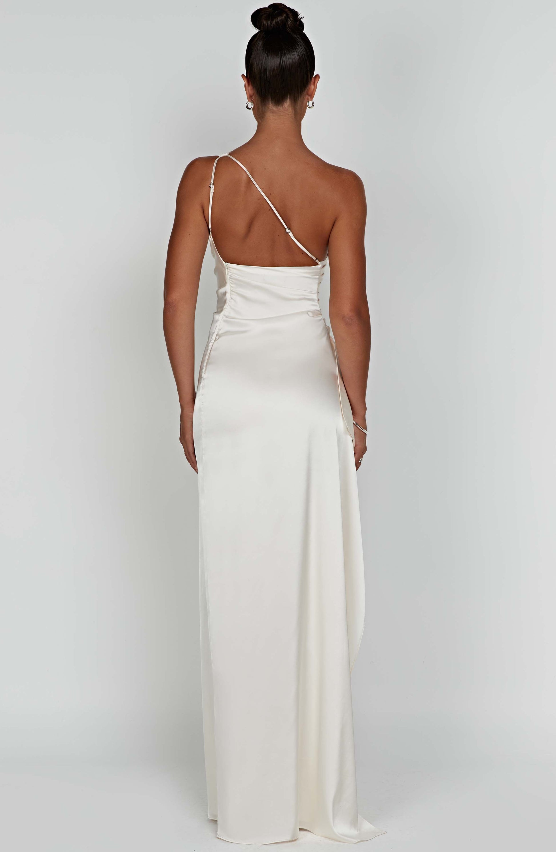 Back view of the off-white one-shoulder draped maxi dress with a delicate strap and flowing skirt.