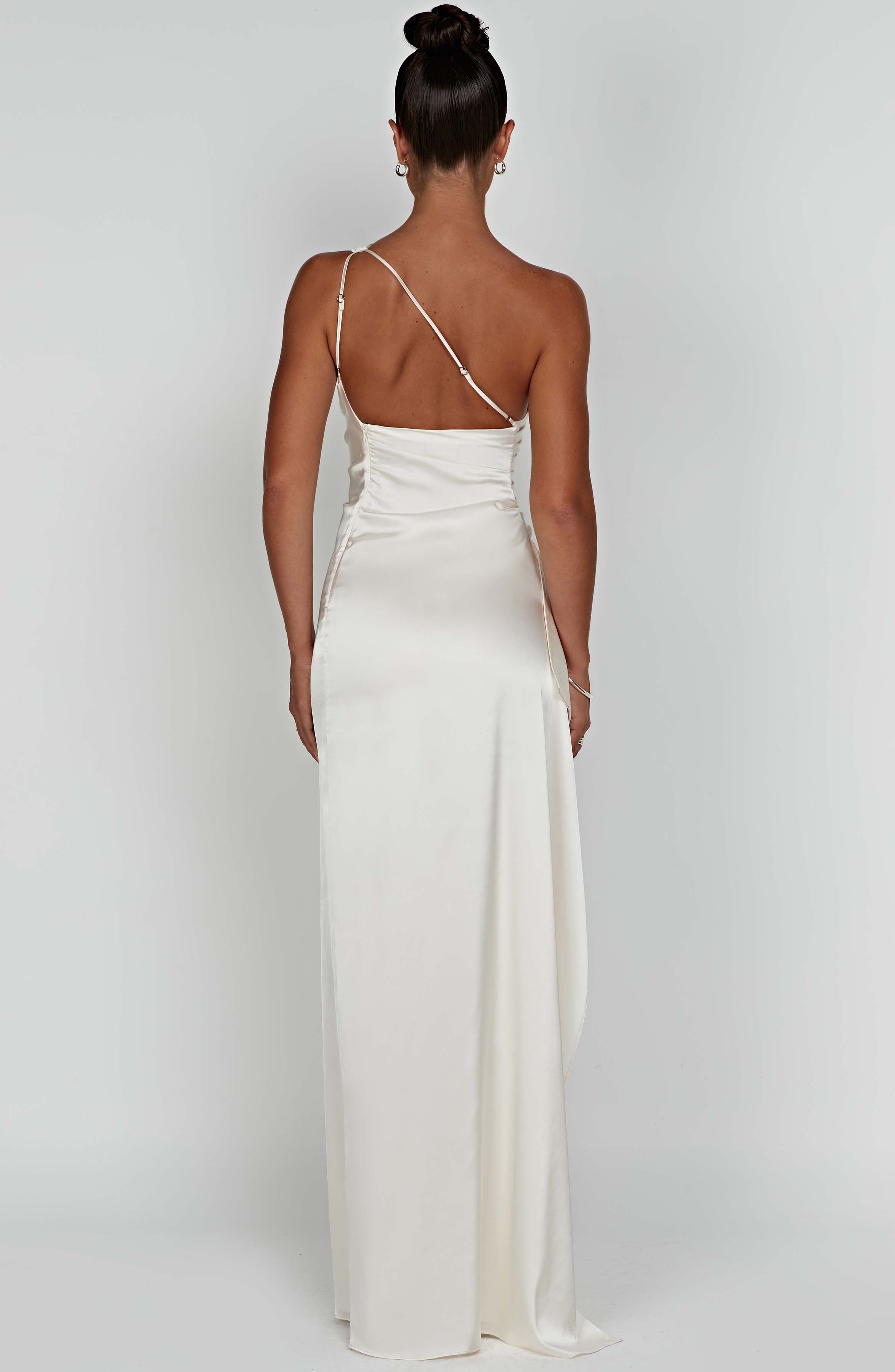 Back view of the off-white one-shoulder draped maxi dress with a delicate strap and flowing skirt.
