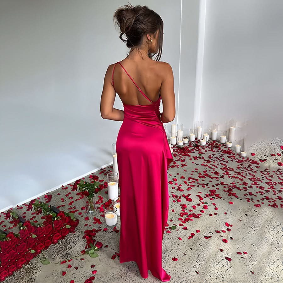 Back view of a fuchsia pink one-shoulder draped maxi dress, highlighting the delicate back strap and flowing skirt.