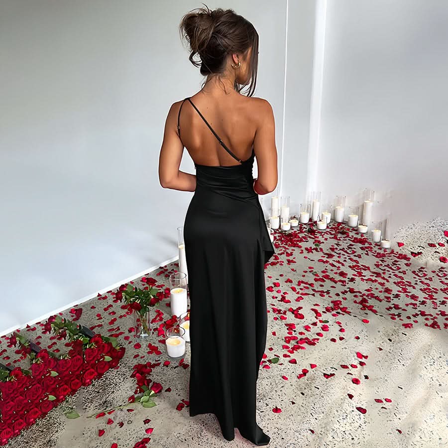 Back of a black one-shoulder draped maxi dress, showing the single thin strap and floor-length skirt.