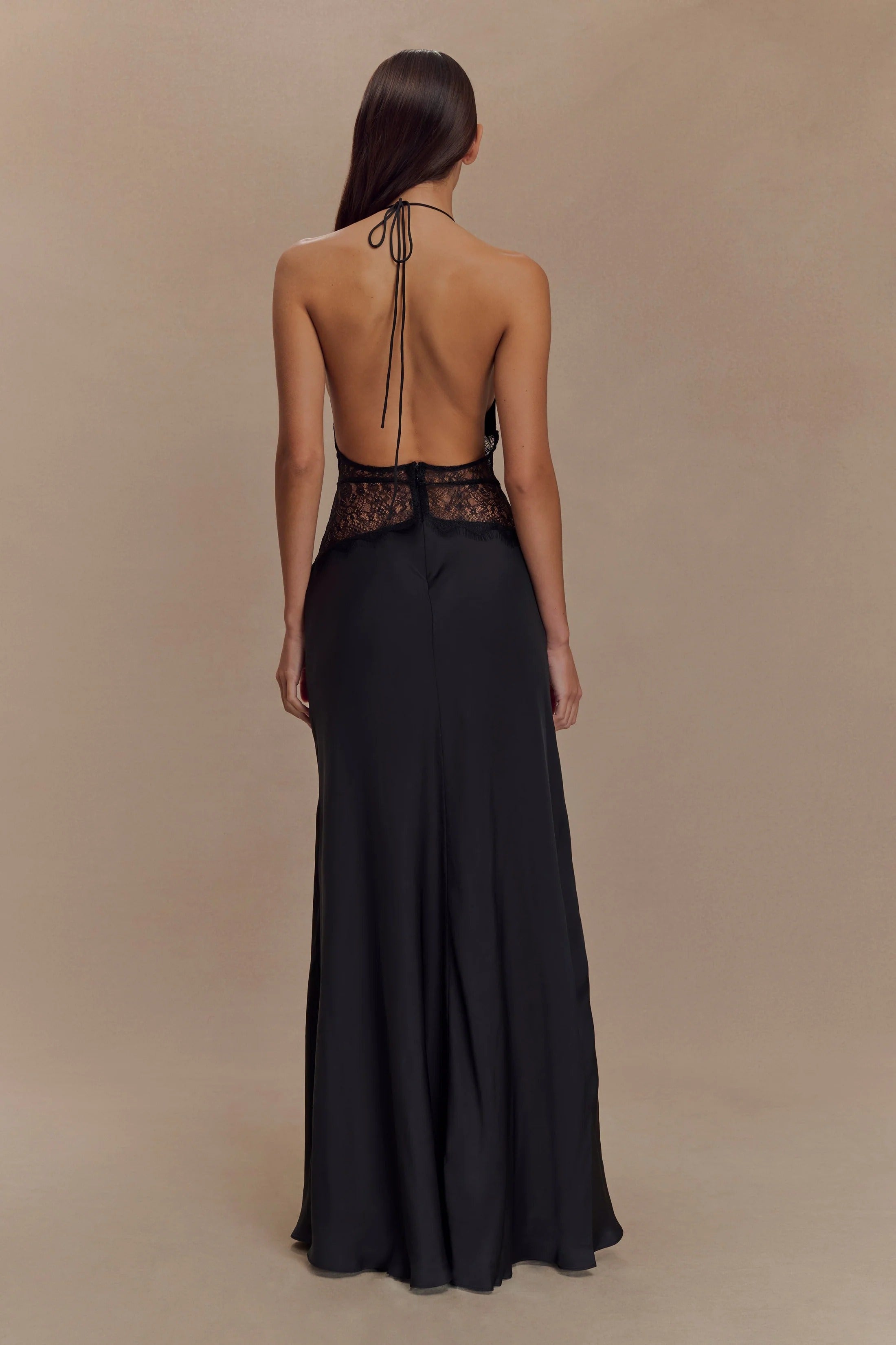 Rear view of the black Skye Lace Maxi Dress, showing the open back design, halter tie, and lace trim.