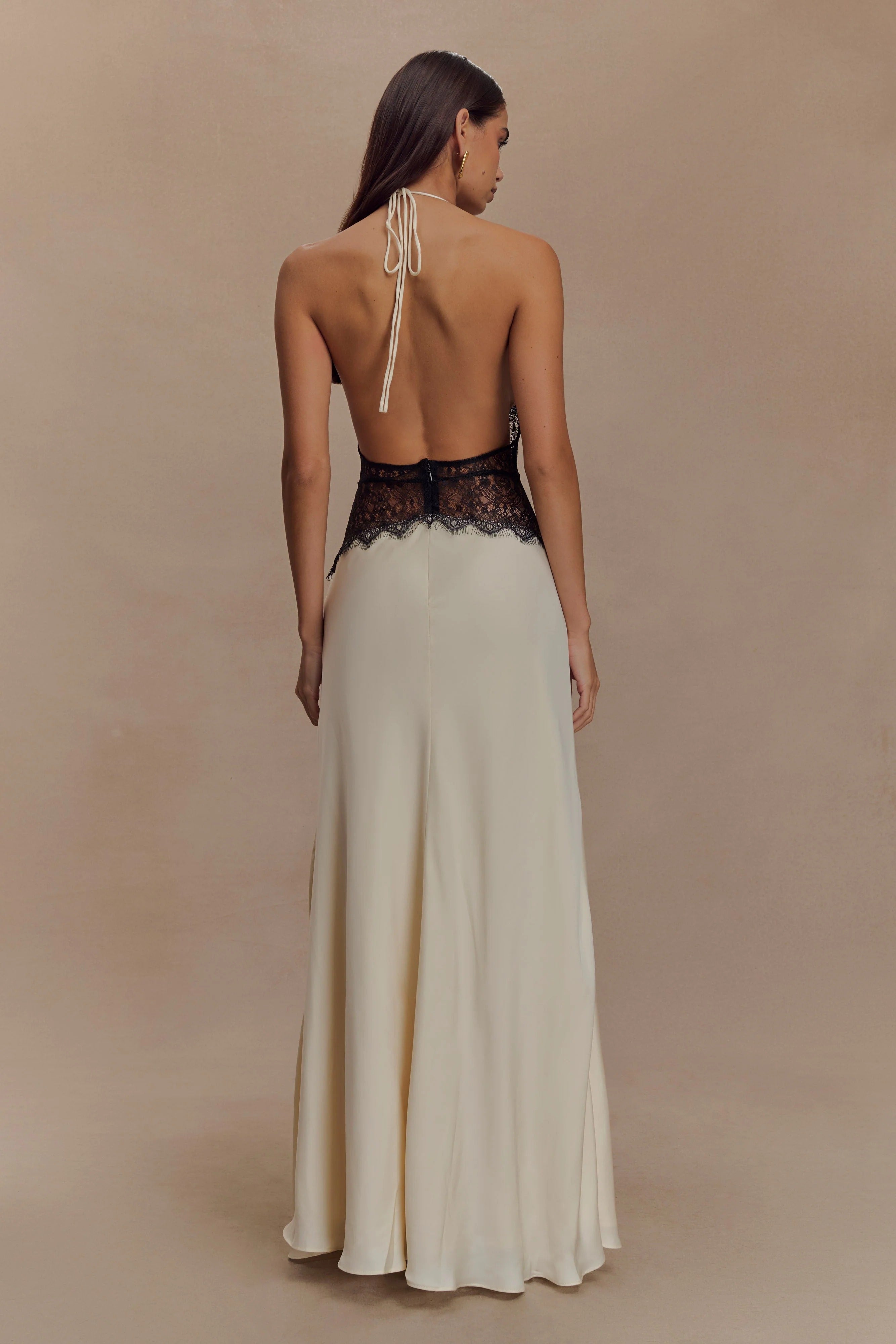 Back view of the cream Skye Lace Maxi Dress, showing the open back with halter tie and black lace detail.