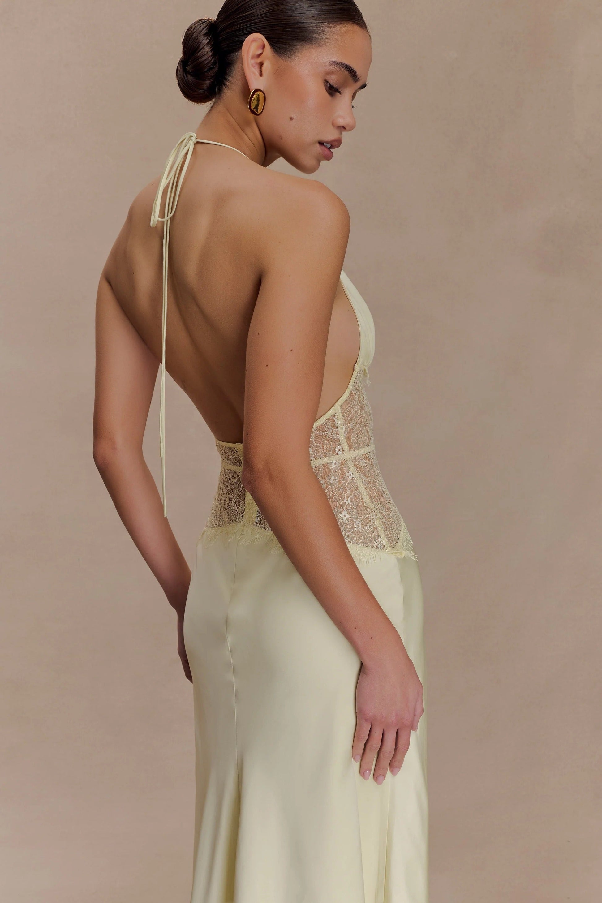 Side view of the light yellow Skye Lace Maxi Dress, showcasing the open back and detailed yellow lace on the bodice.