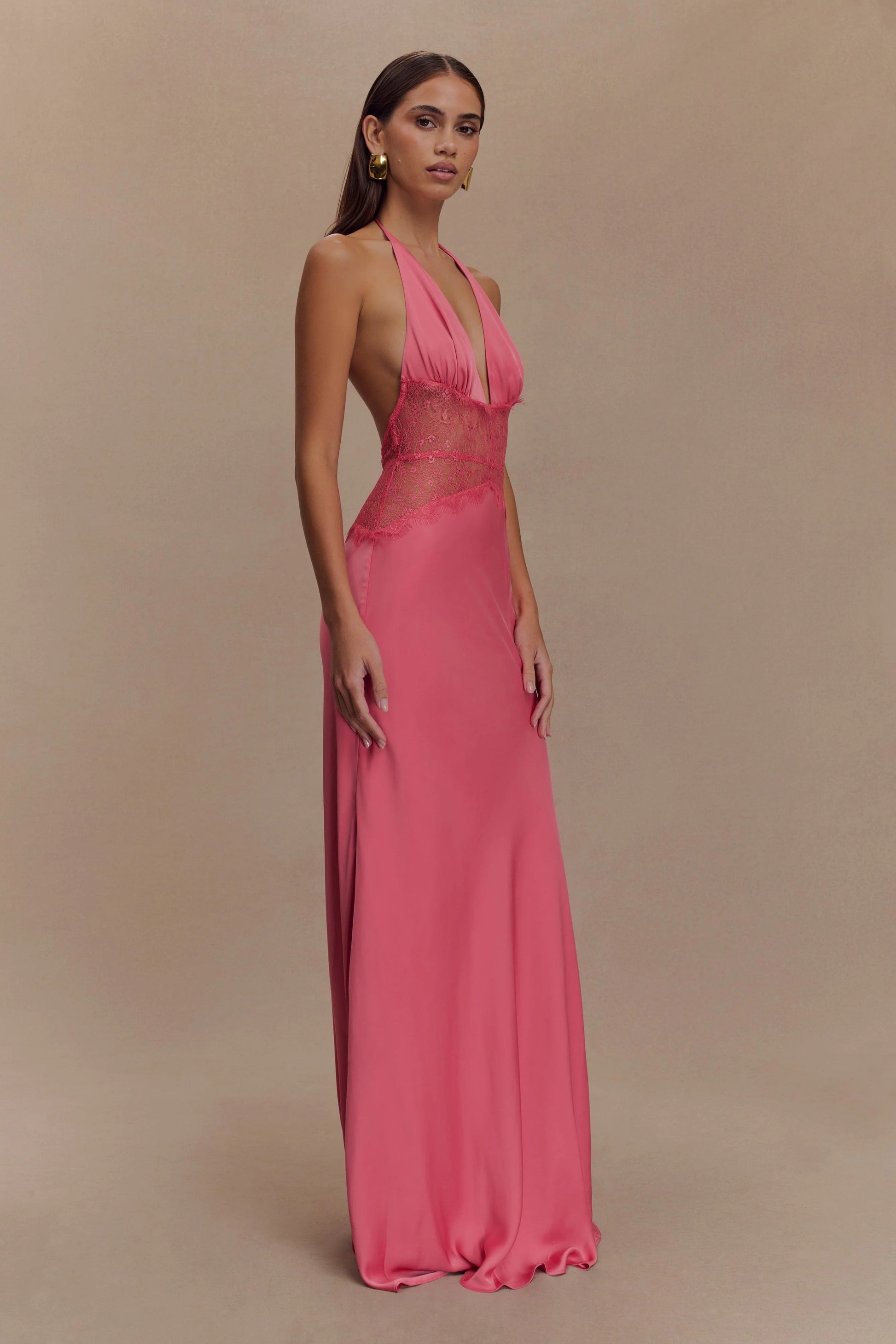 Side profile of a vibrant pink Skye Lace Maxi Dress with a deep V-neck and matching pink lace bodice, elegant flowing skirt.