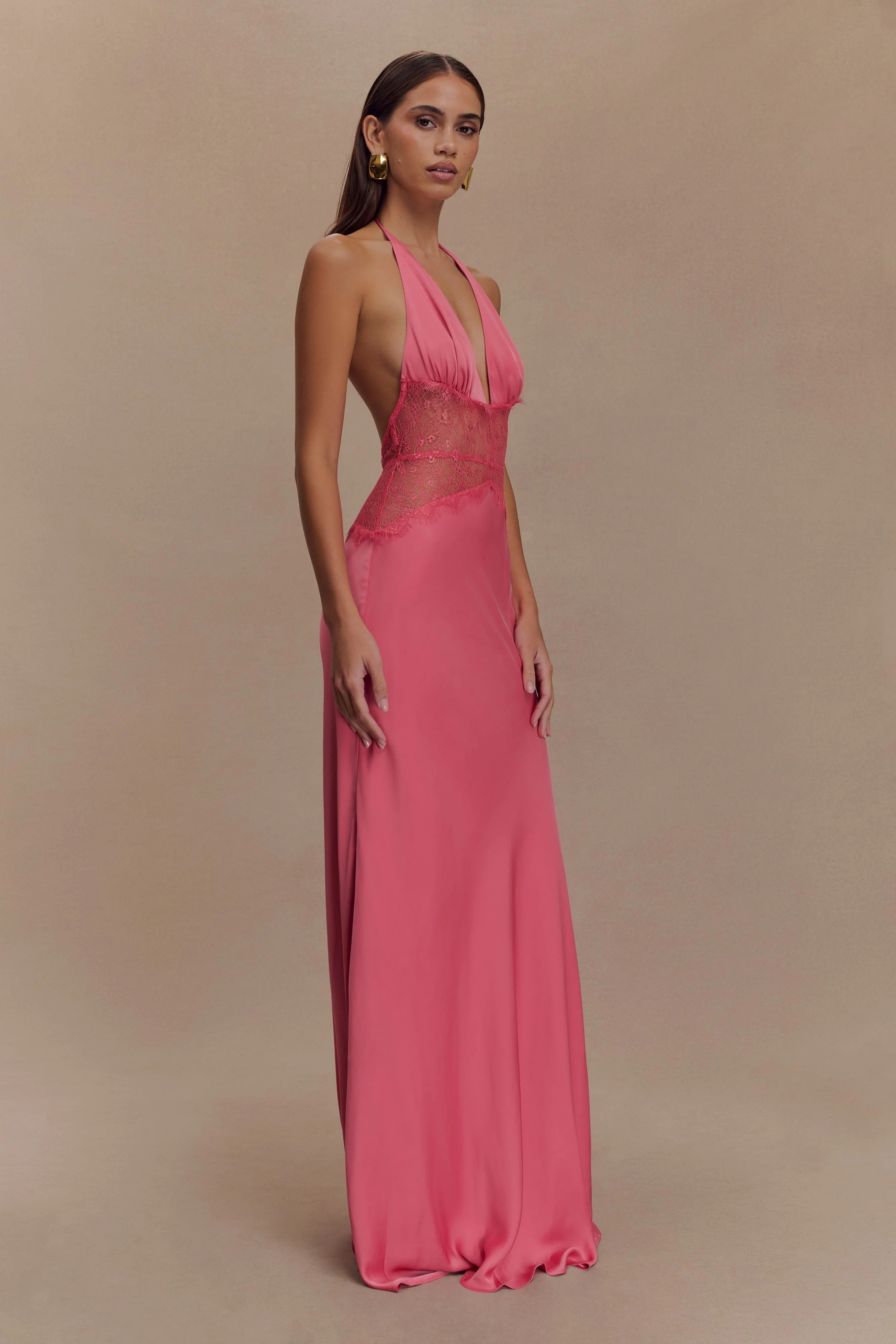 Side profile of a vibrant pink Skye Lace Maxi Dress with a deep V-neck and matching pink lace bodice, elegant flowing skirt.