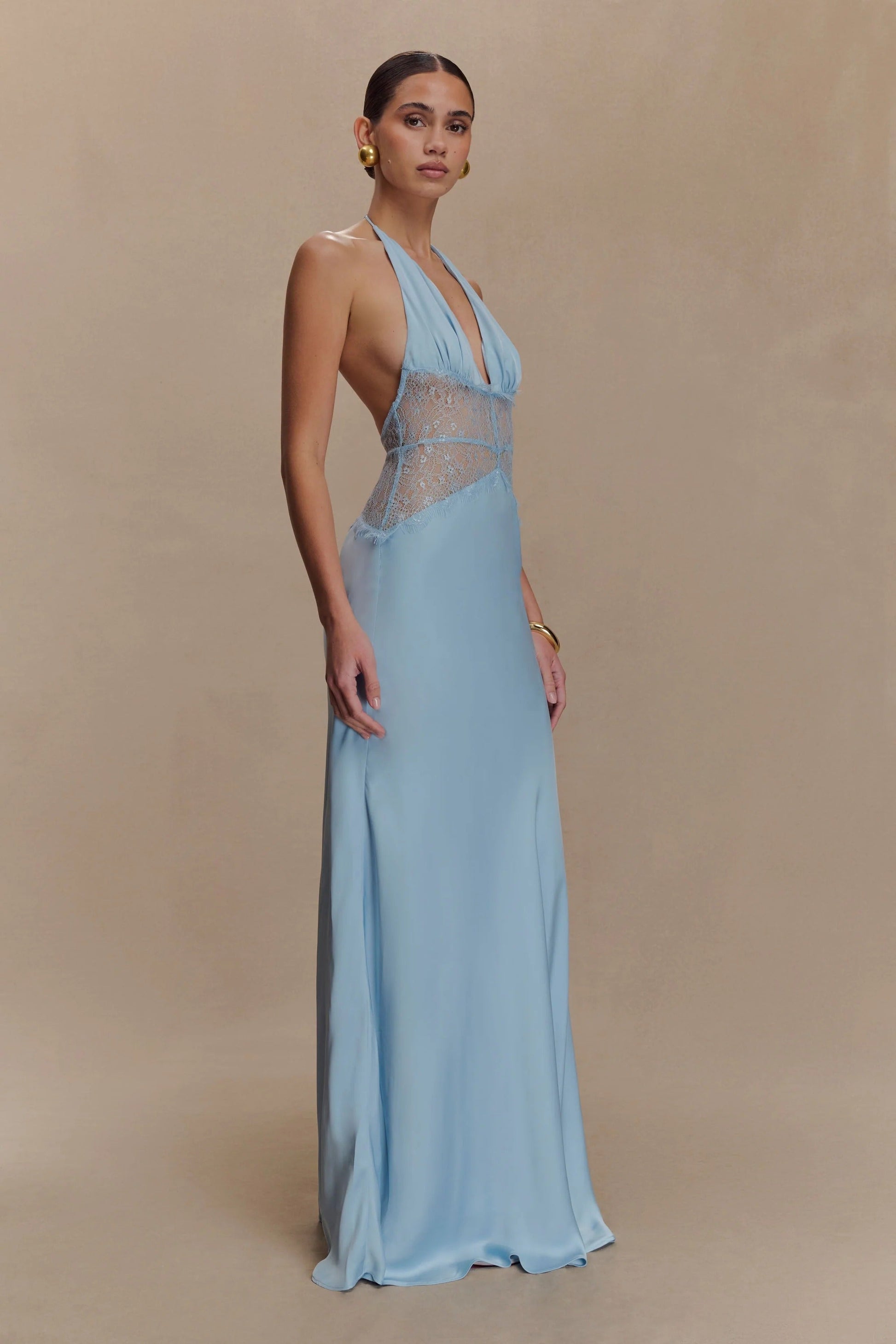 Side profile of a light blue Skye Lace Maxi Dress with a deep V-neck and matching blue lace bodice, smooth flowing skirt.