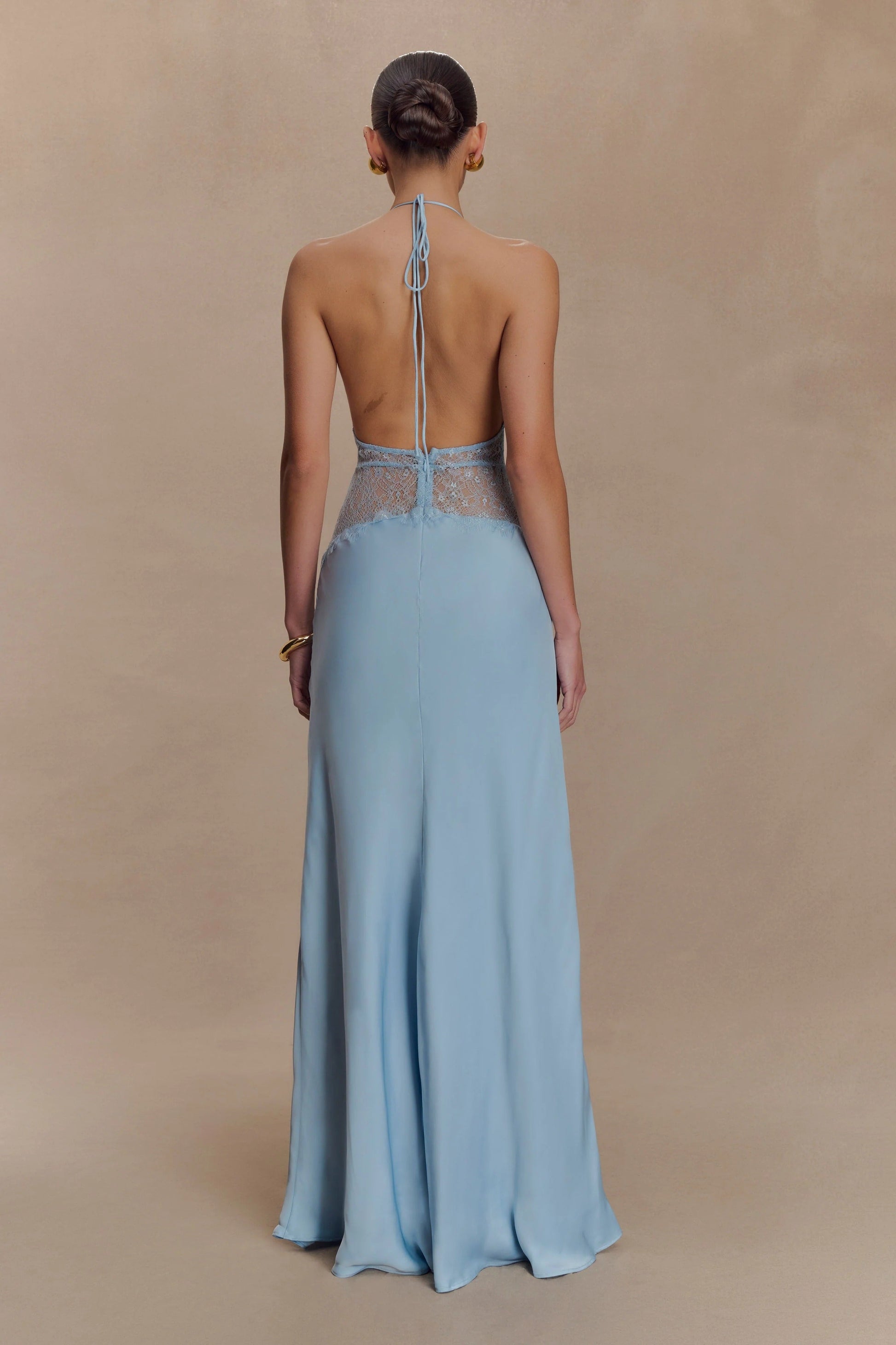 Back view of the light blue Skye Lace Maxi Dress, showing the open back with halter tie and subtle blue lace detail.
