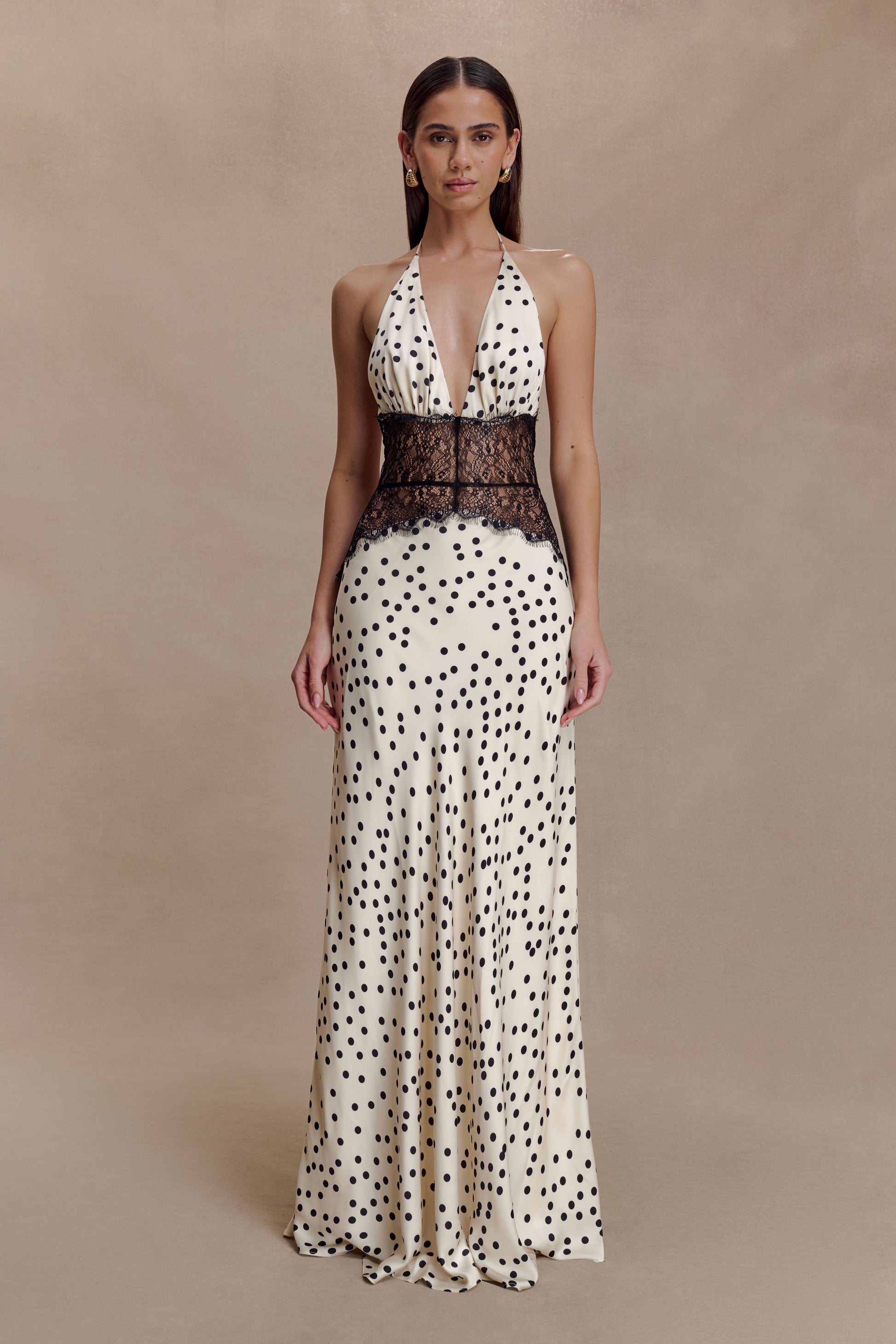 Full-length Skye Lace Maxi Dress in cream with black polka dots, featuring a deep V-neck halter and black lace bodice.