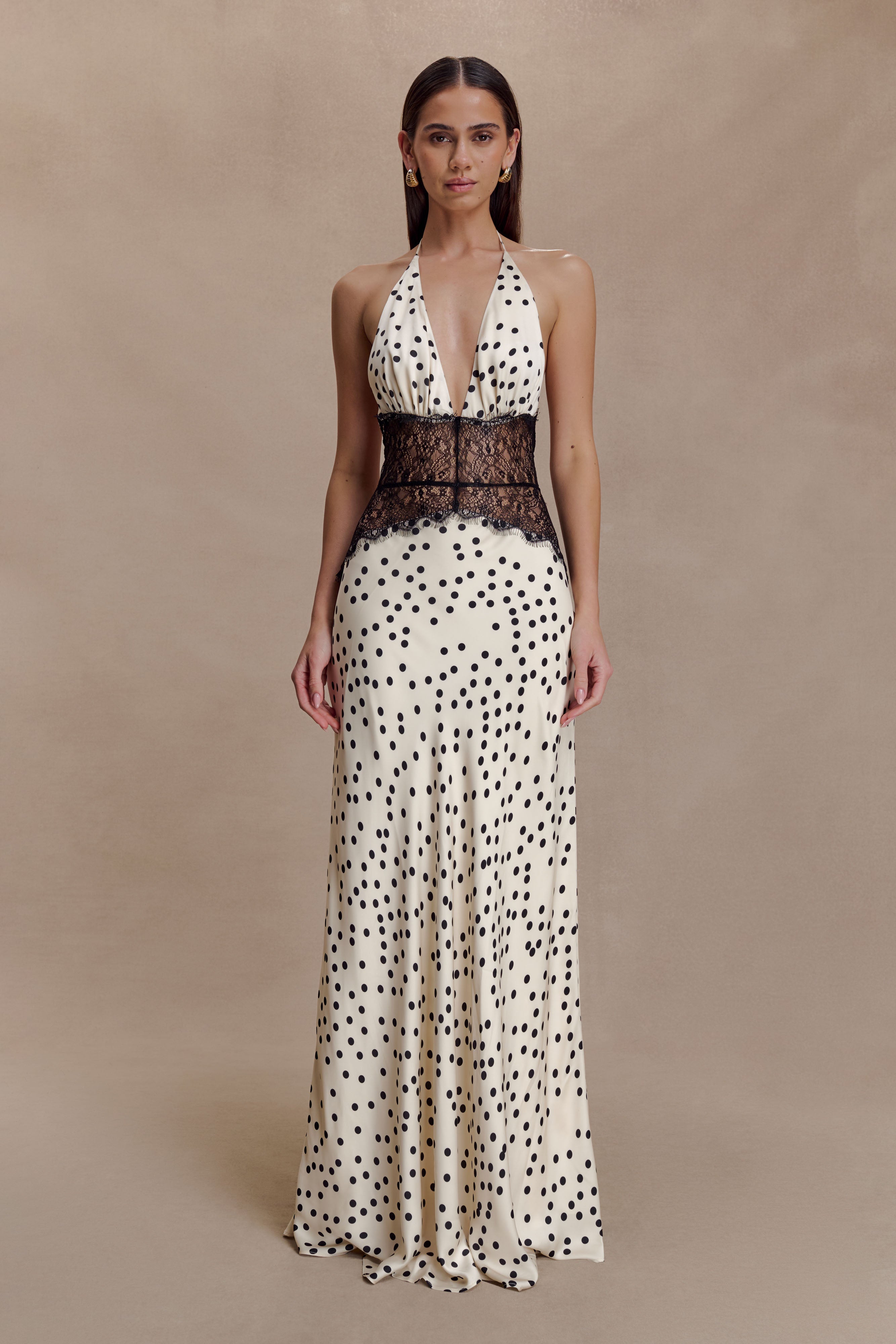 Full-length Skye Lace Maxi Dress in cream with black polka dots, featuring a deep V-neck halter and black lace bodice.