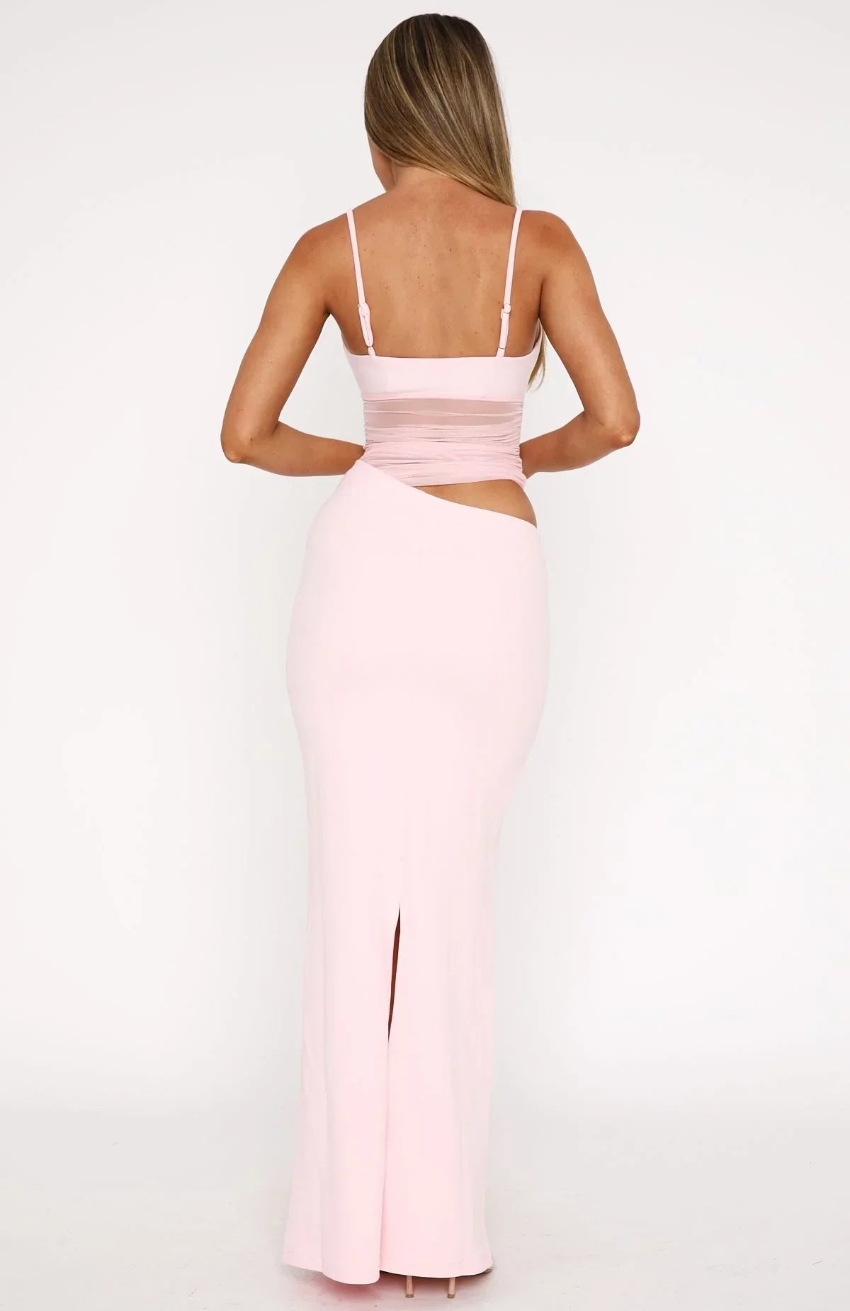 Back view of the light pink Skylar Cutout Maxi Dress, showing the open back detail and skirt slit.