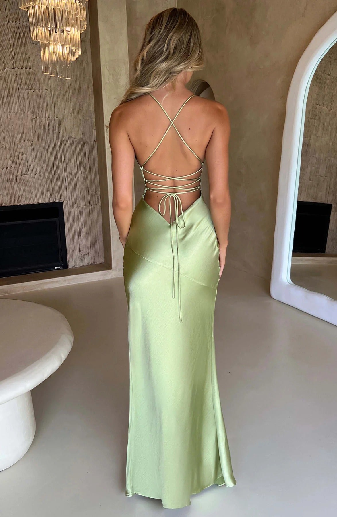 Rear view of the light green satin maxi dress, highlighting the elegant criss-cross back straps and flowing skirt.