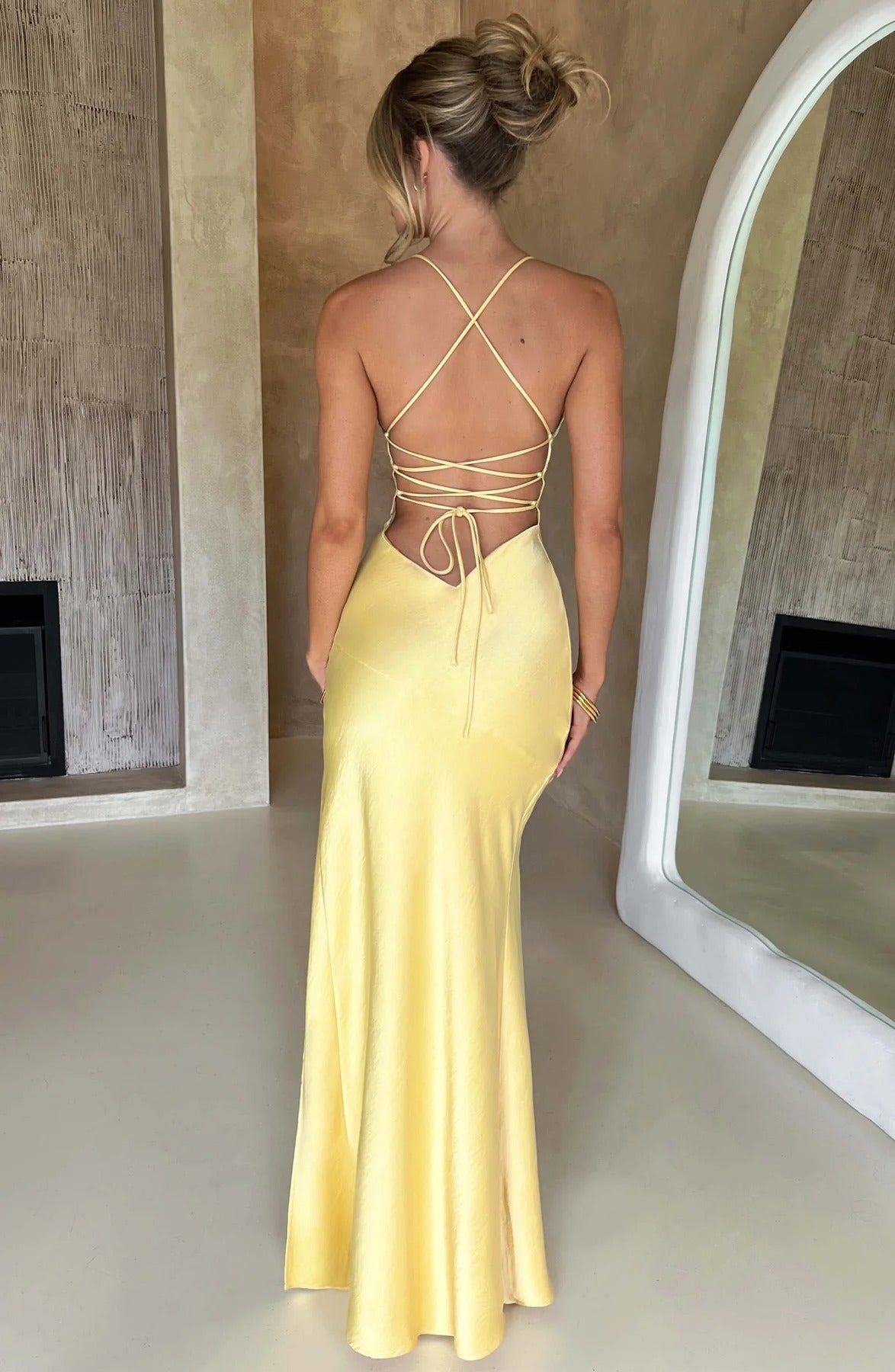 Back of a bright yellow satin maxi dress, displaying the detailed criss-cross strap design and open back.