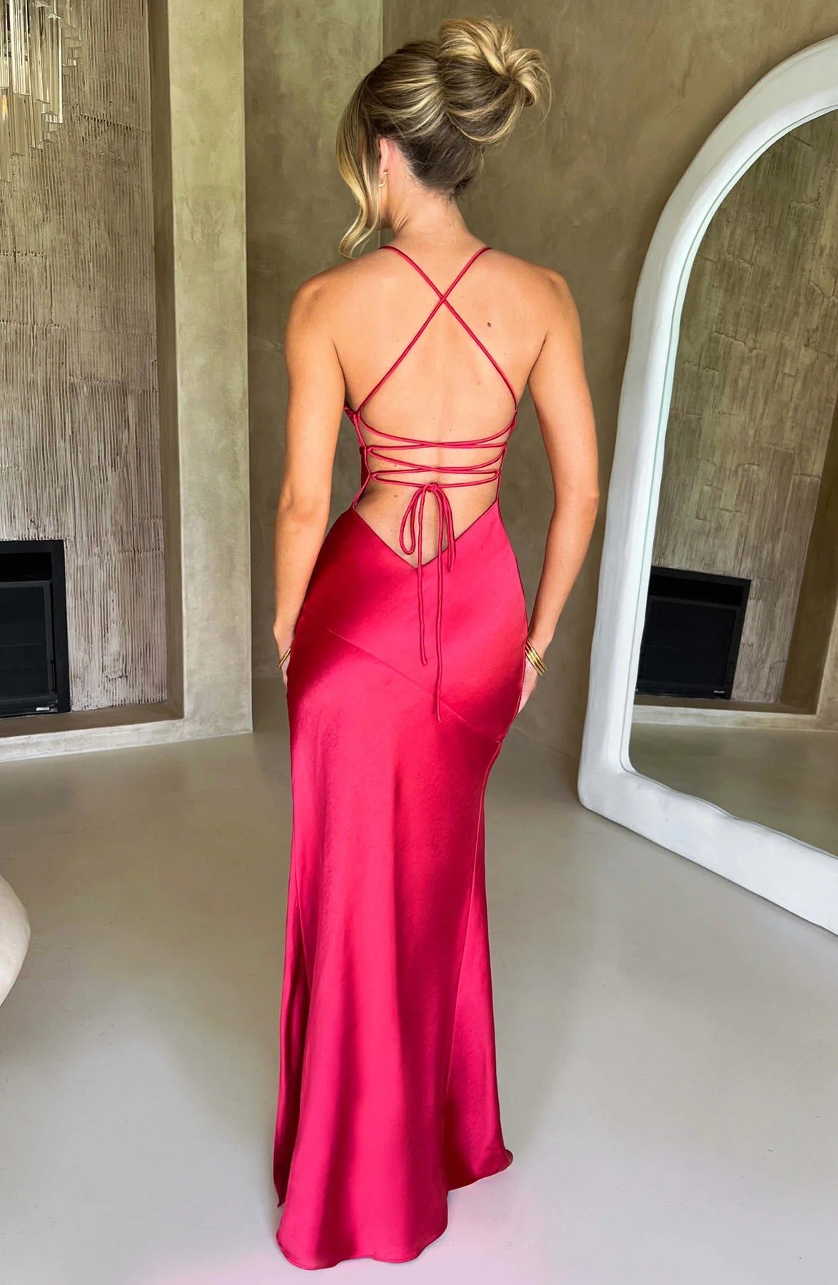 Back view of the striking red satin maxi dress, showcasing the intricate lace-up back detail and flowing silhouette.
