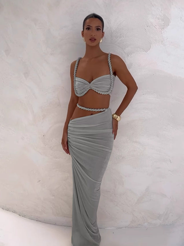 Woman posing in a light grey braided maxi set, showcasing the bandeau top and draped maxi skirt with a side cutout detail.