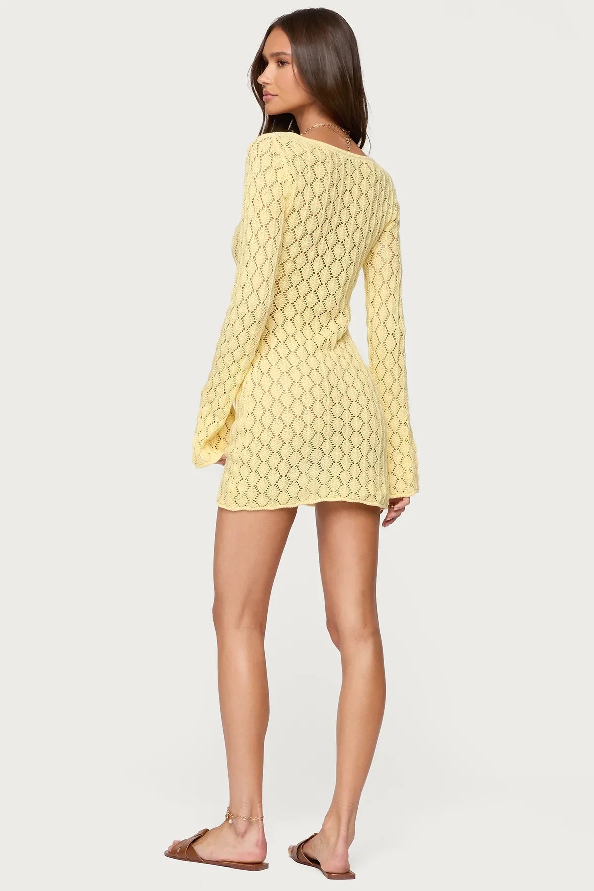 Back view of a woman wearing a yellow crochet keyhole mini dress, highlighting the diamond knit pattern.