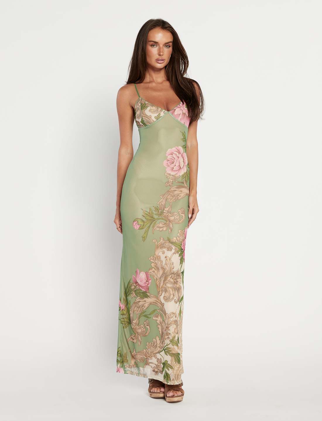 Full length view of Thea Floral Maxi Dress in sage green with pink floral and baroque print, worn by a model against a grey wall.