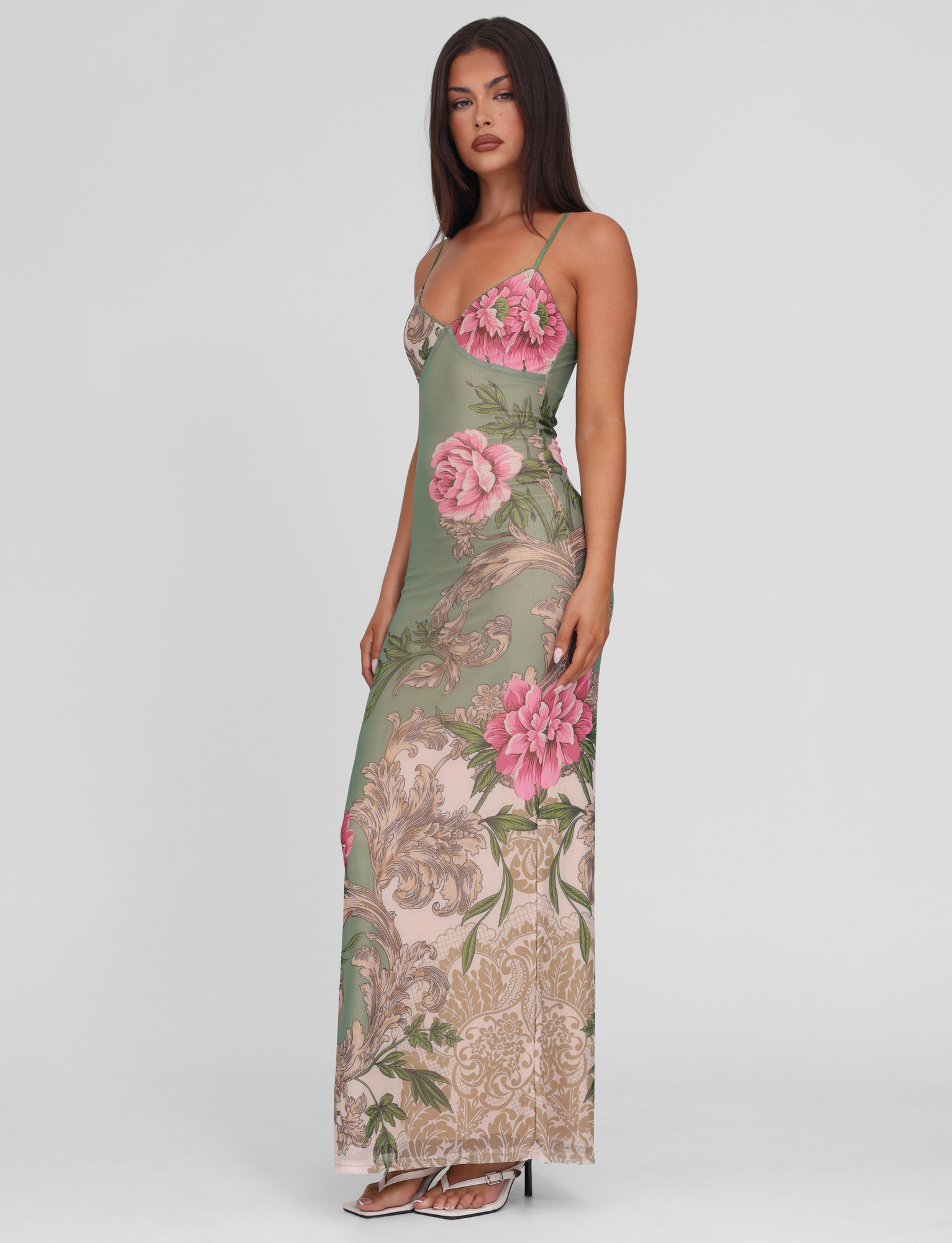 Side profile of a model wearing the Thea Floral Maxi Dress, highlighting the full length and intricate floral and baroque pattern.
