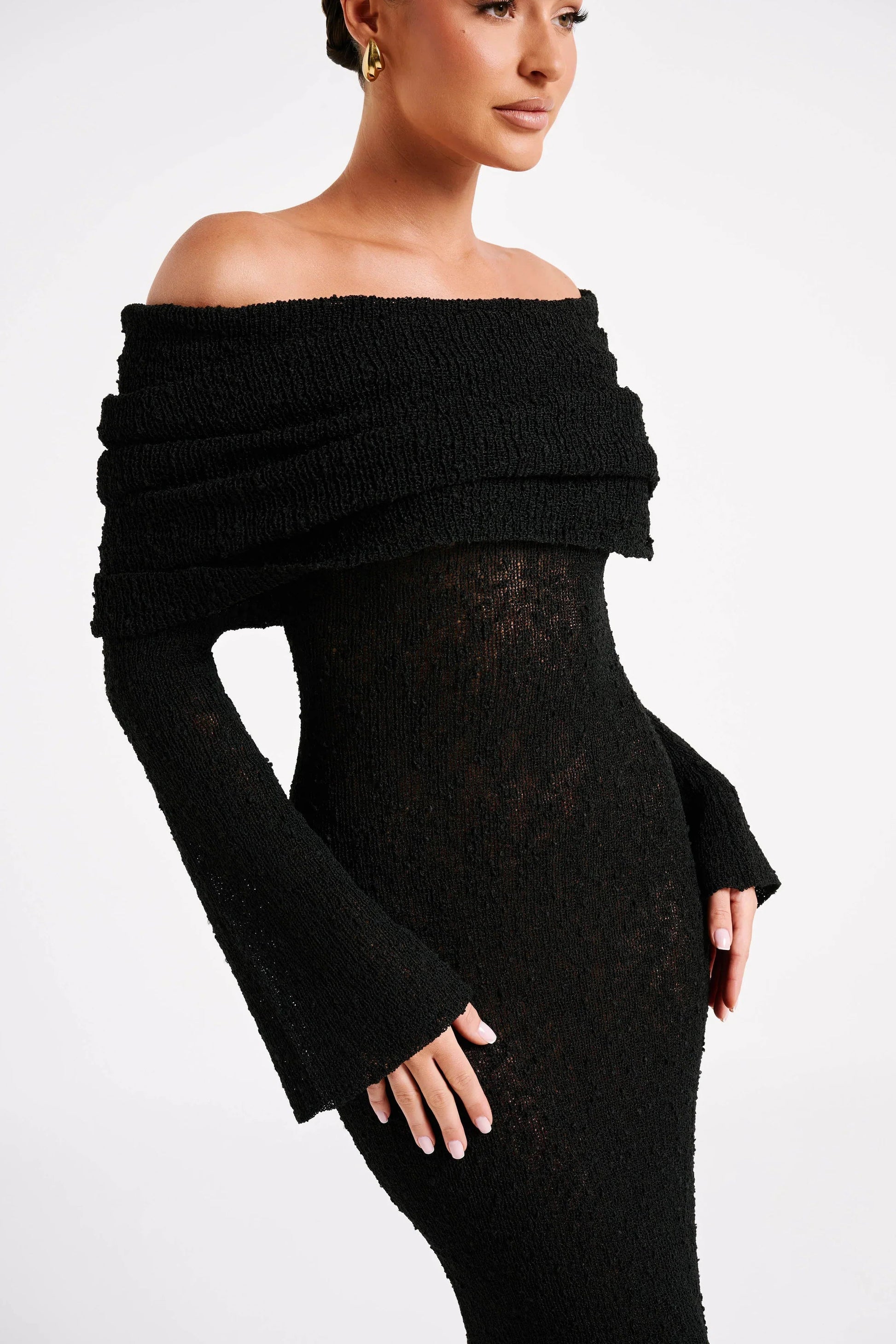 Close-up of black Valencia Drape Maxi Dress, showing off-the-shoulder draped detail and textured knit fabric.