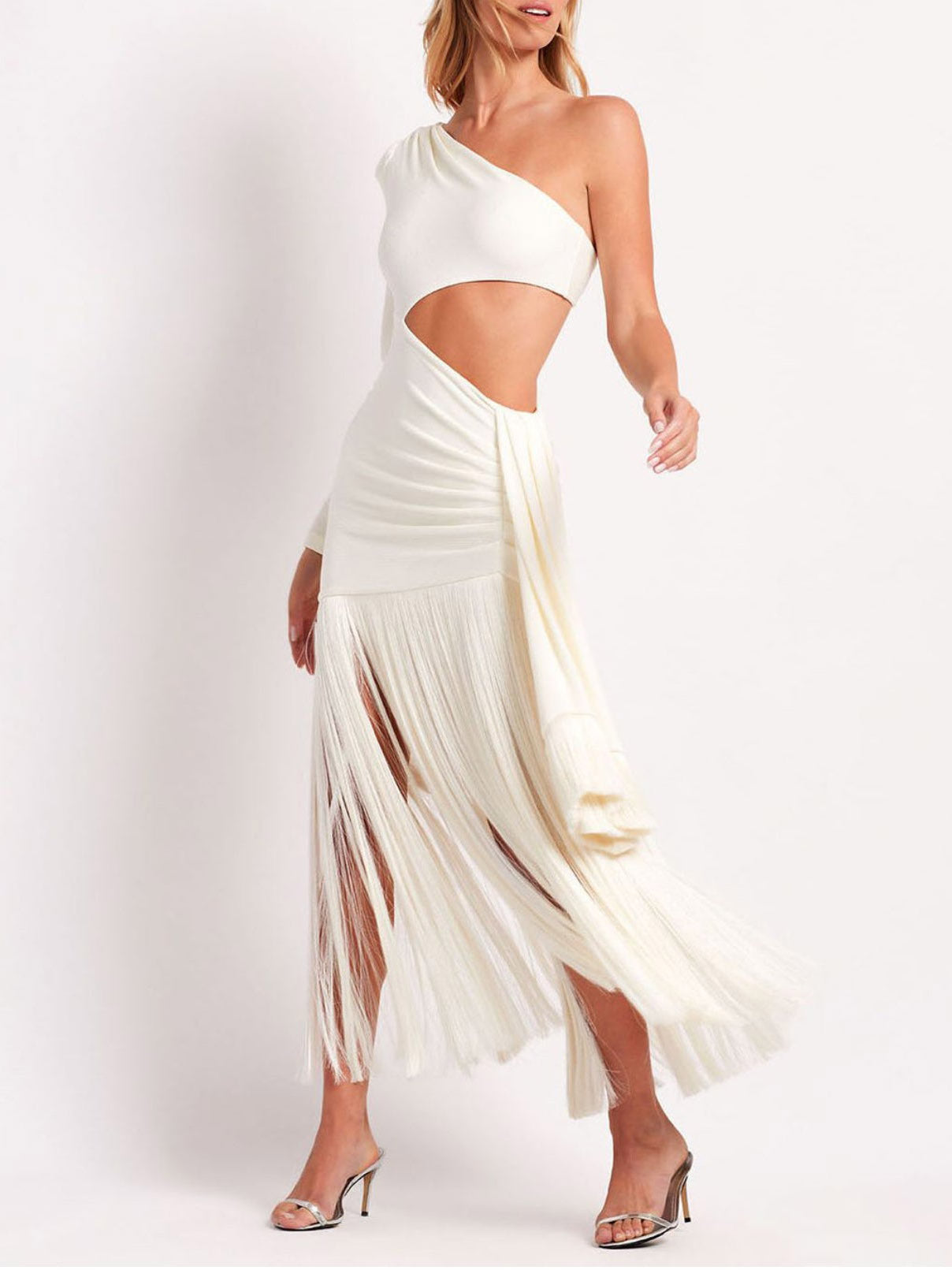 White one-shoulder maxi dress with a side cutout, long sleeve, and a dynamic fringe skirt in motion.
