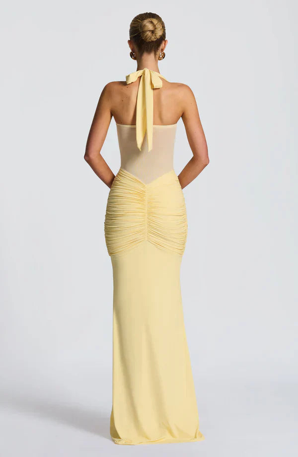 Back view of the pale yellow Victoria ruched maxi dress, with a tied halter neck and a fully ruched rear skirt section.