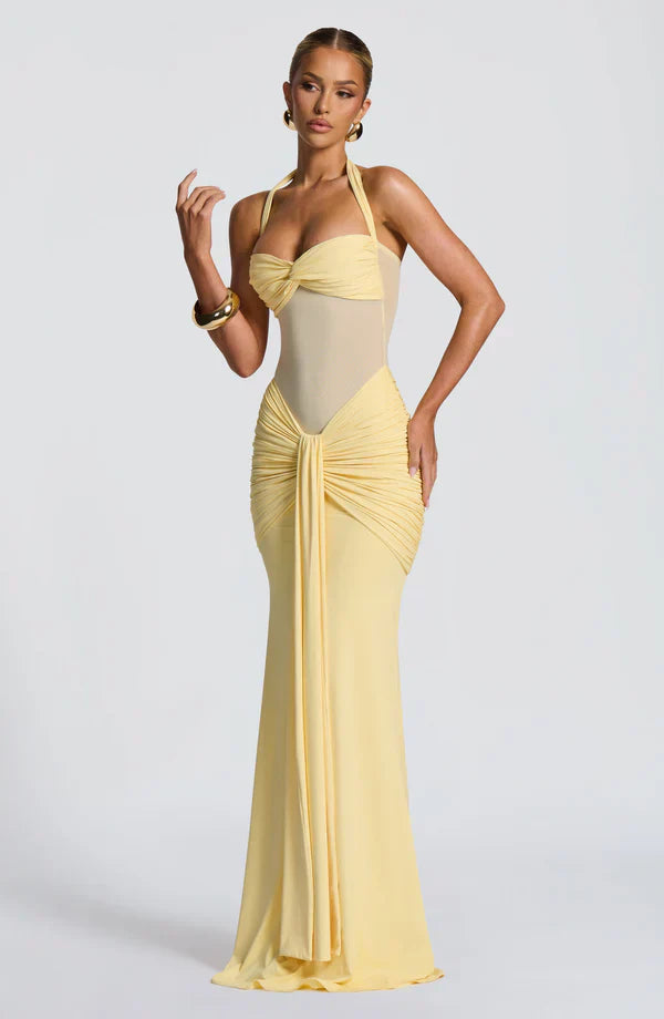 Full-length pale yellow ruched maxi dress with halter neckline and sheer midsection detail, perfect for women's evening wear.